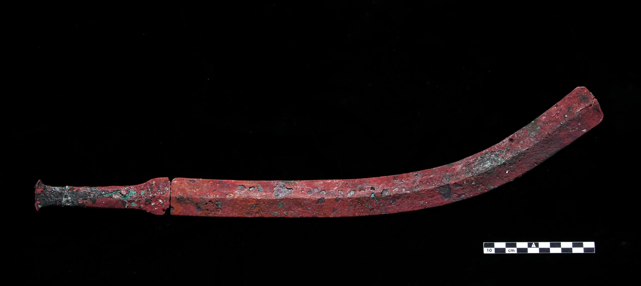 Curved bronze blade photographed on black velvet with scale bar, Saudi Arabia