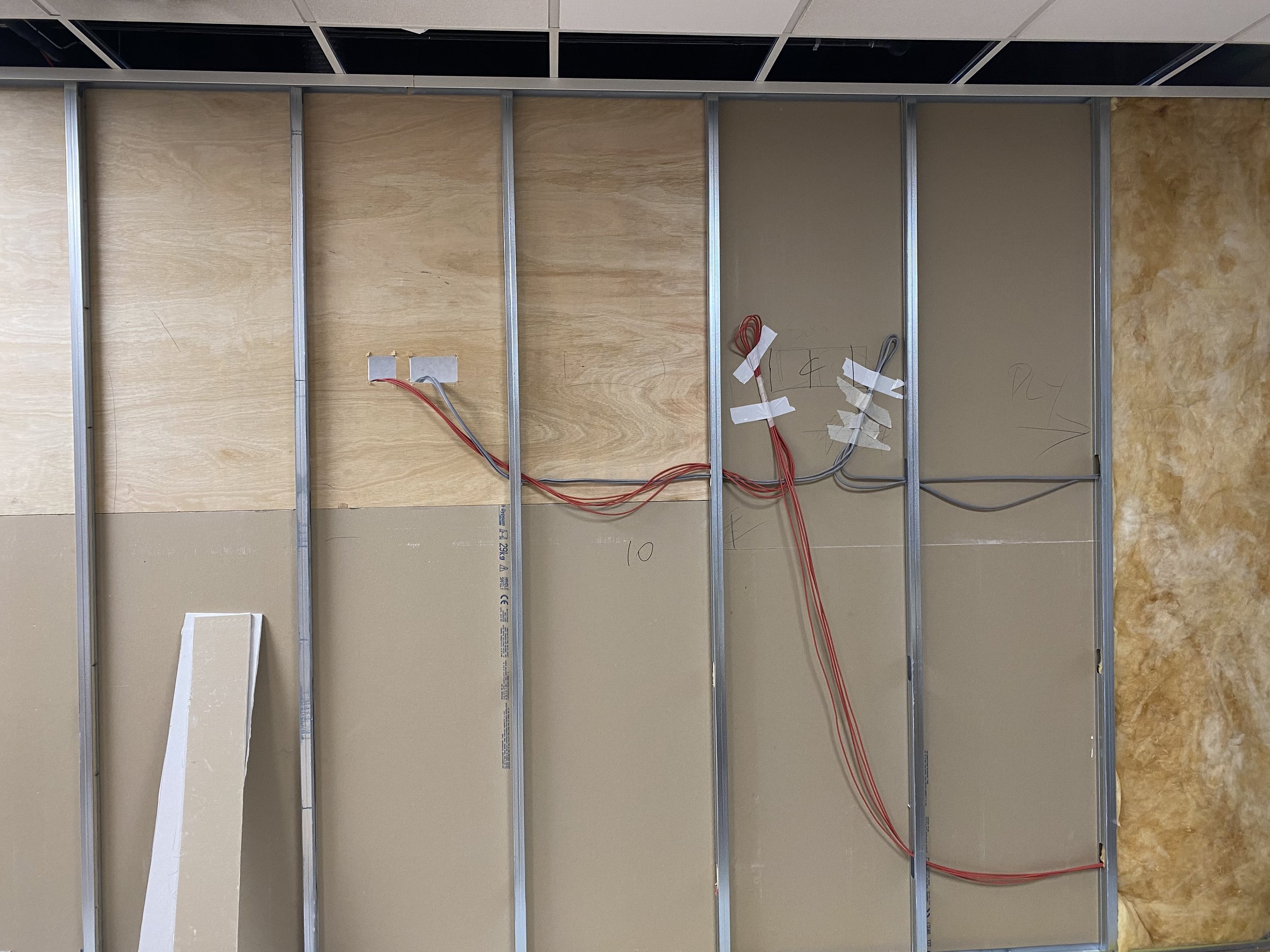 Construction wall framing with exposed wiring and insulation.