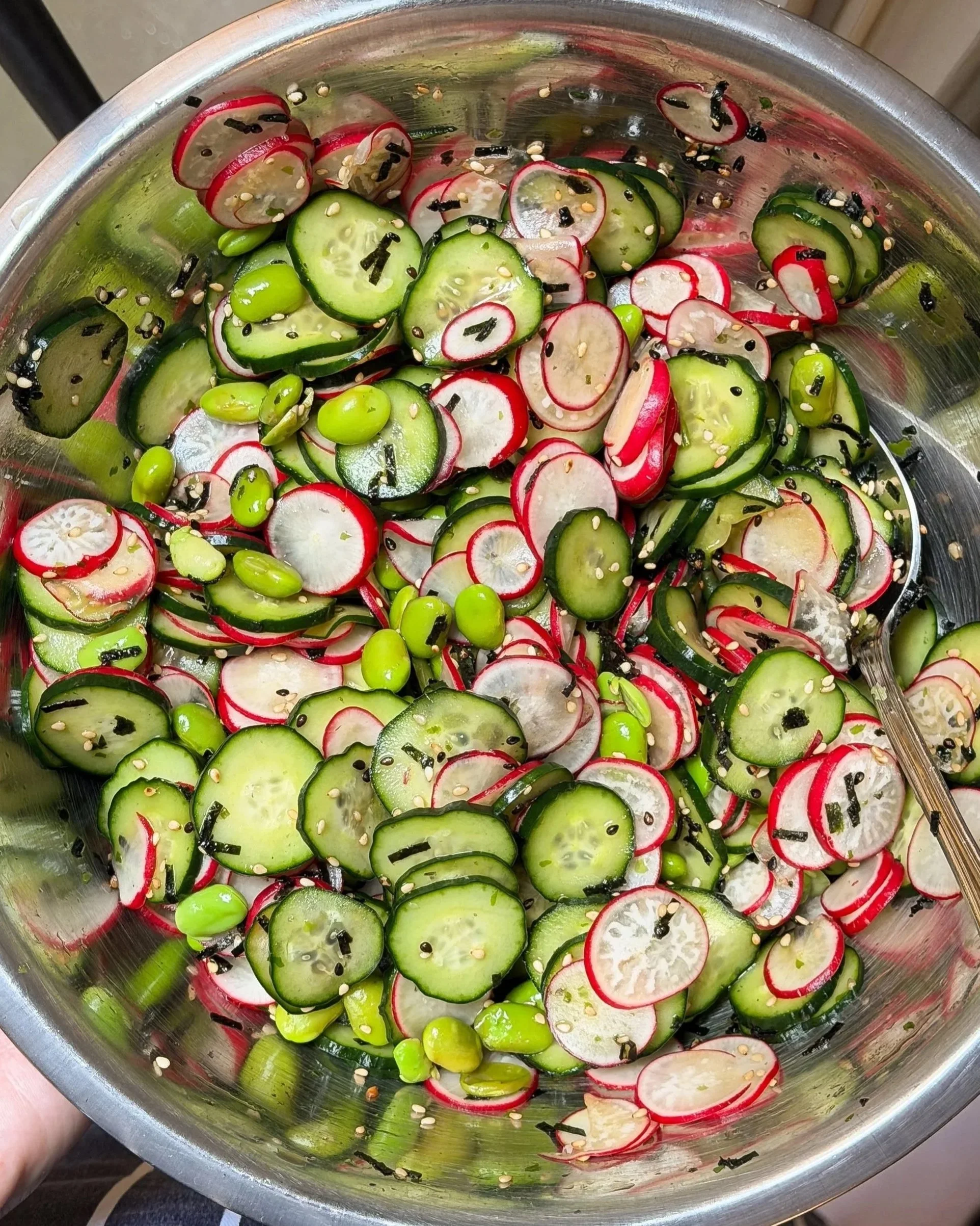 A refreshing dense bean salad for hot days, with sliced cucumbers, radishes, and edamame inside a stainless steel bowl.