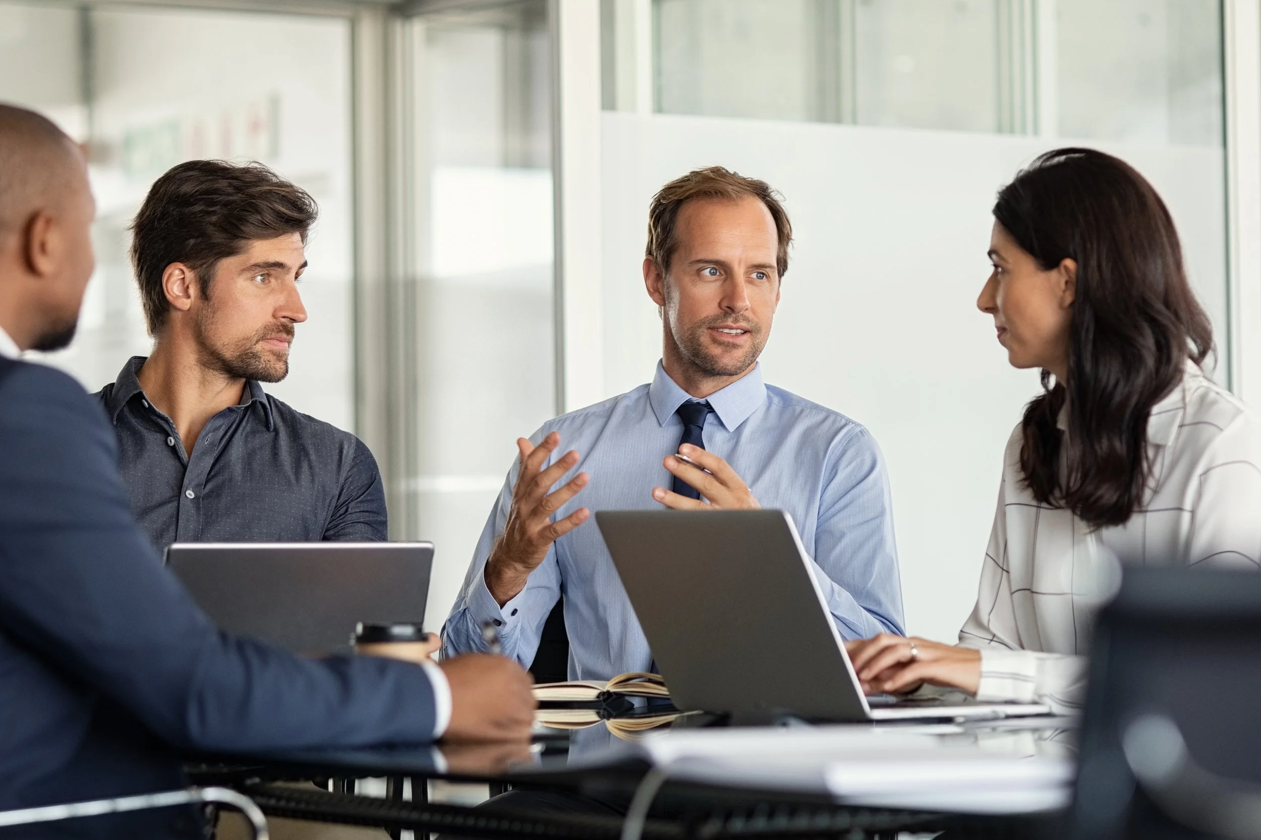 Picture of colleagues meeting around a conference table with laptops.