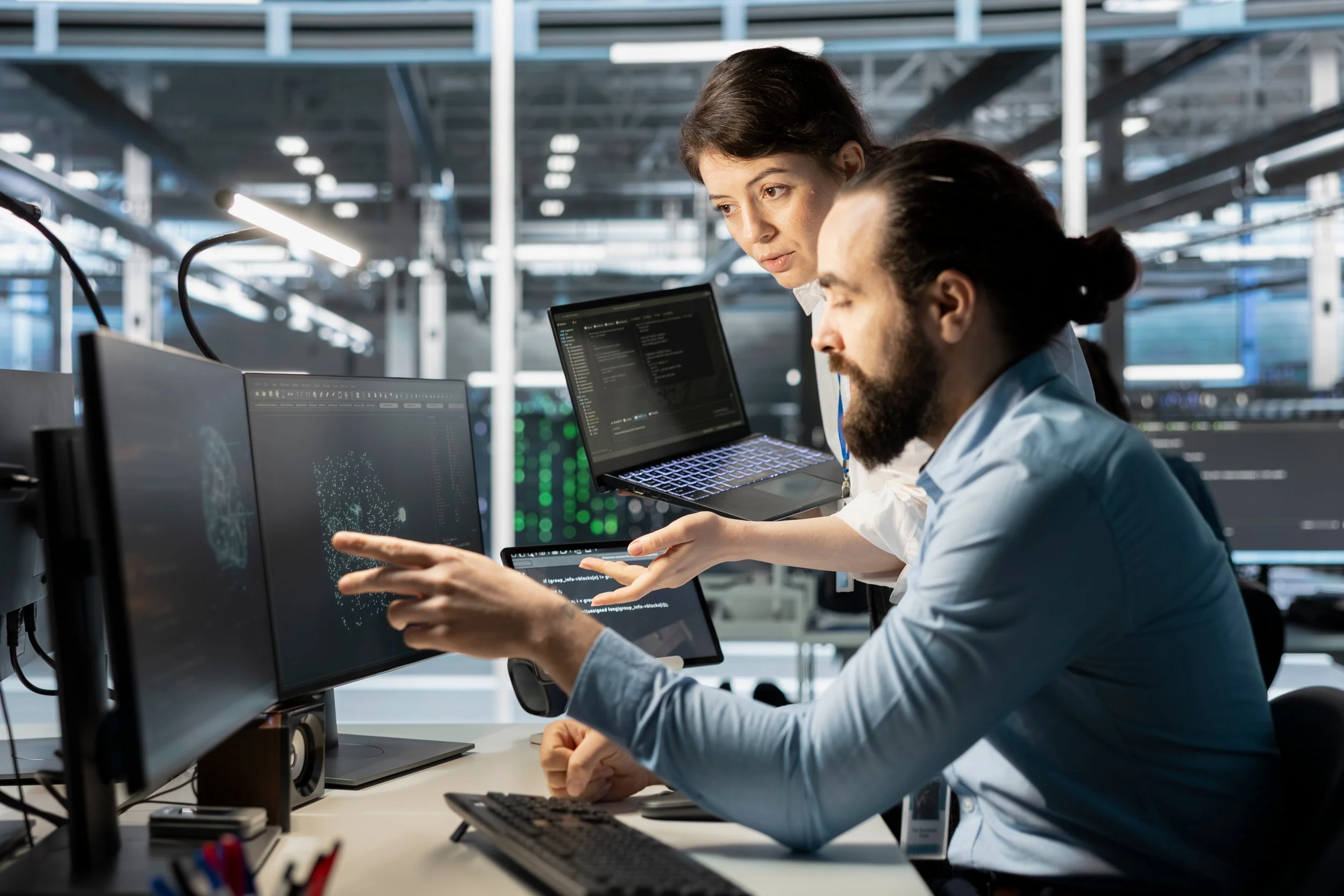Picture of two professionals analyzing data on computer screens in a modern tech workspace.