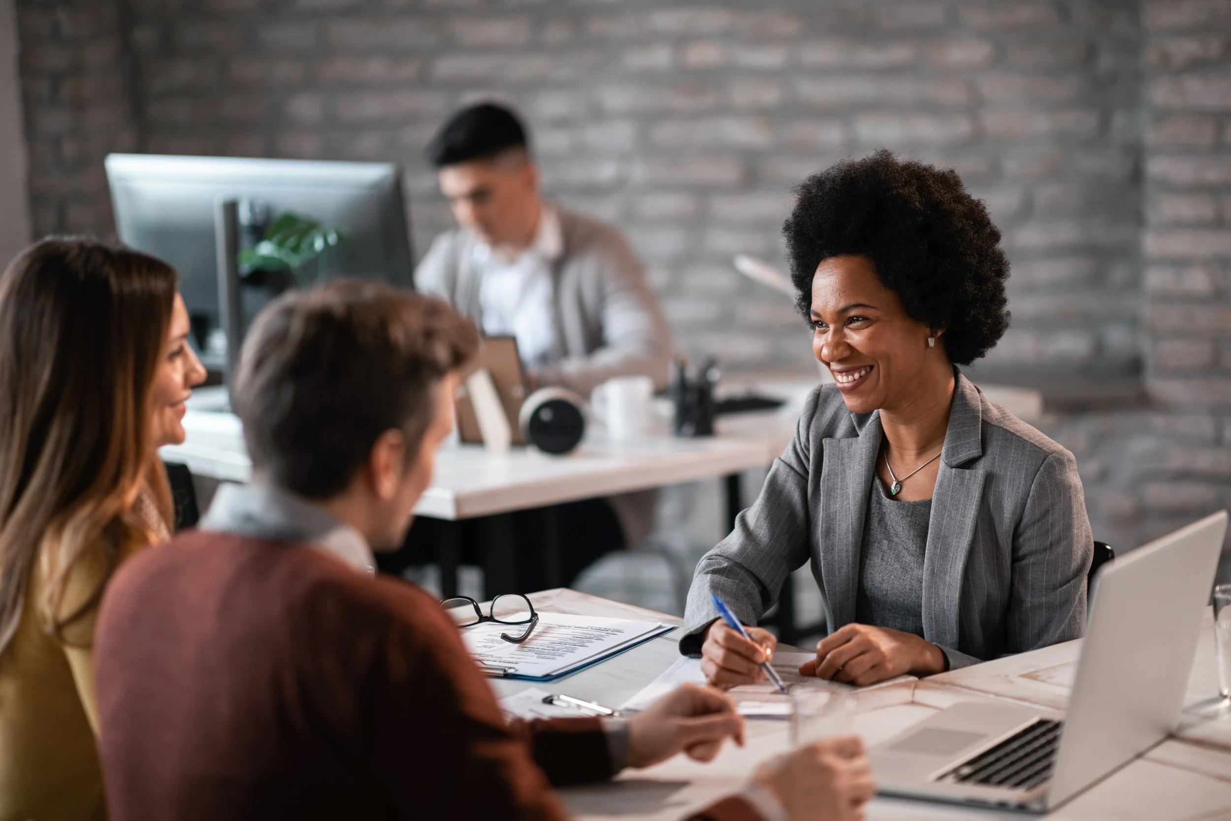  Picture of people discussing documents at an office desk with a laptop.