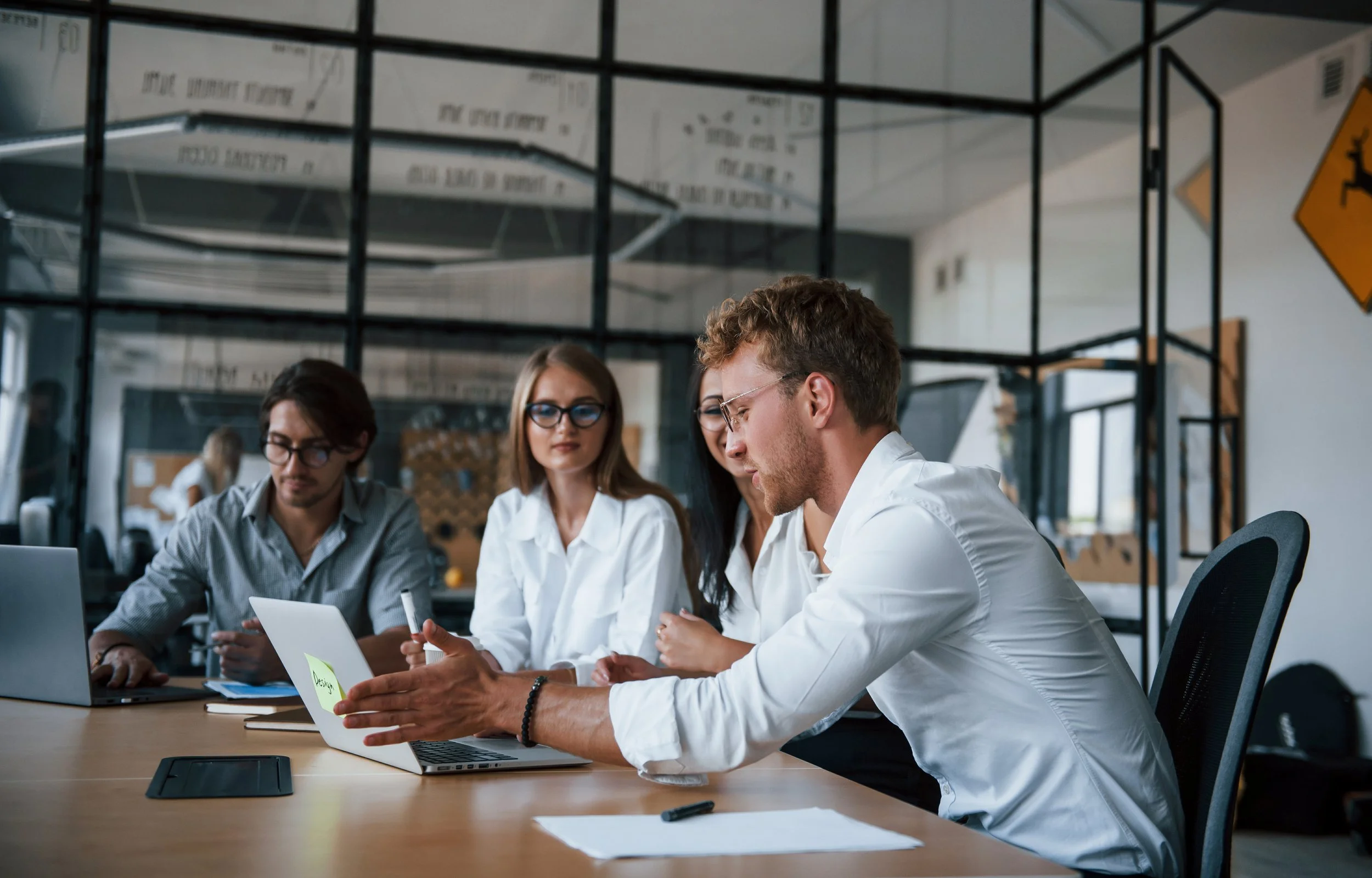 Picture of a team meeting around a conference table with laptops and documents.