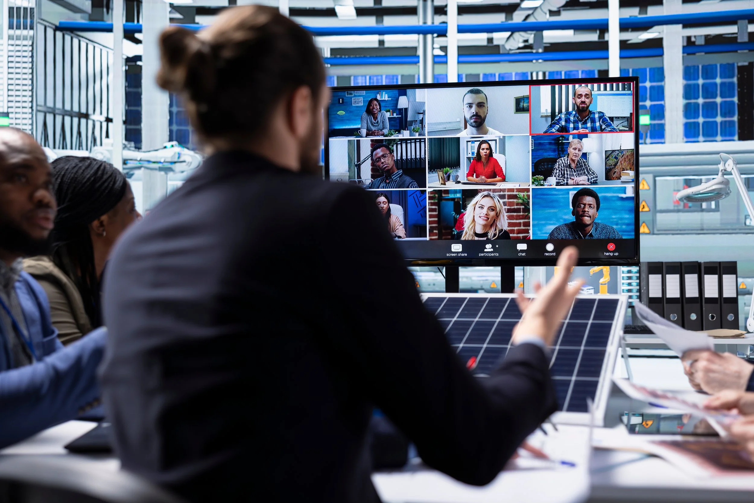 A picture of a team meeting with remote participants on a video conference screen.