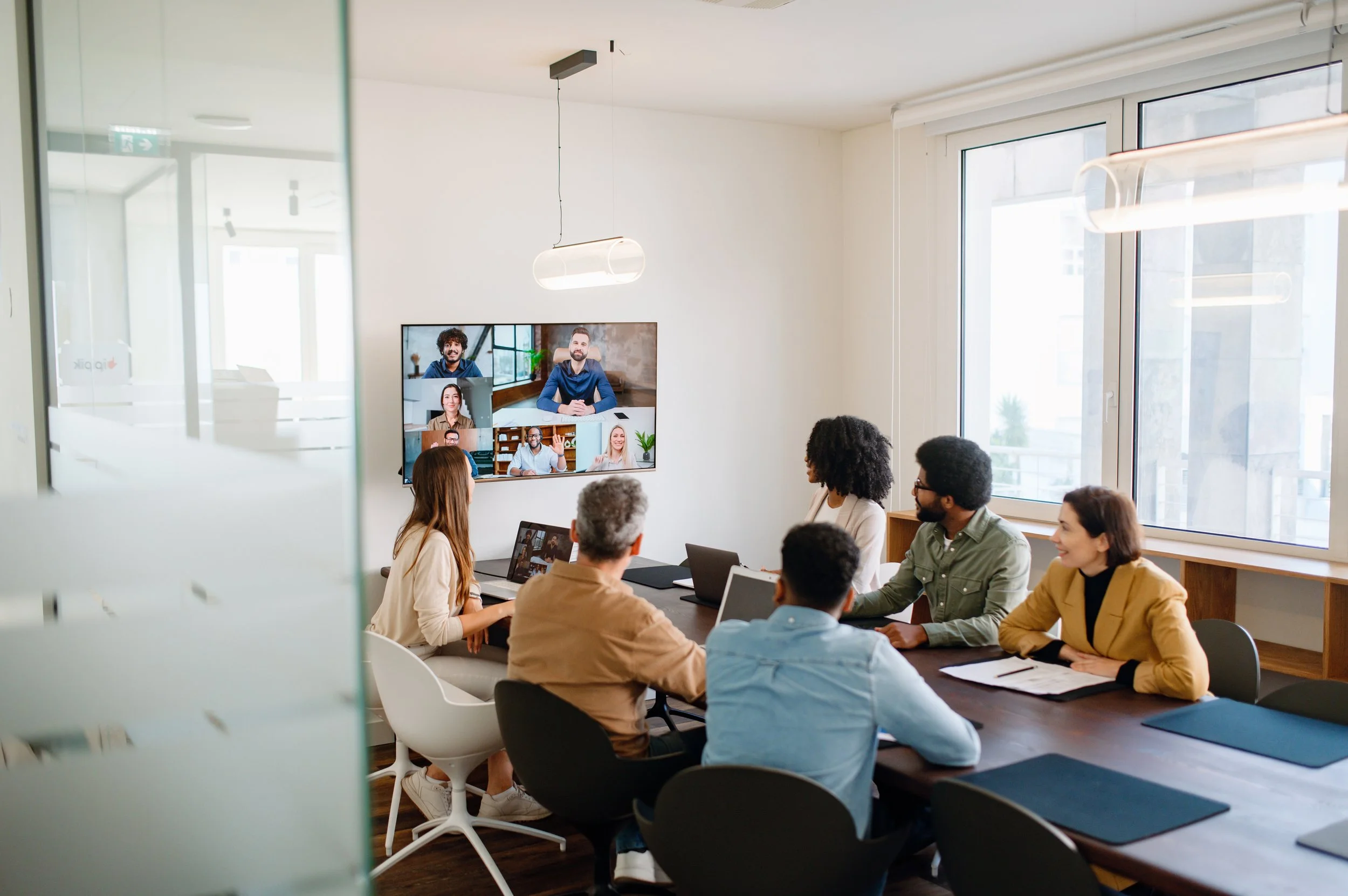 Picture of a team meeting in a conference room with a video call on screen.