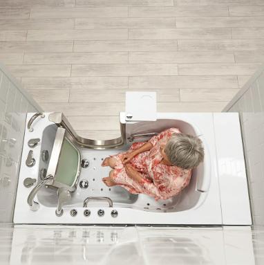 Top-down view of a person sitting inside a stand-in shower with a shower chair in a modern bathroom.