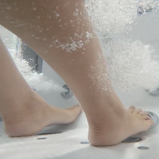 Close-up of a person's bare feet standing on a shower floor, water splashing.
