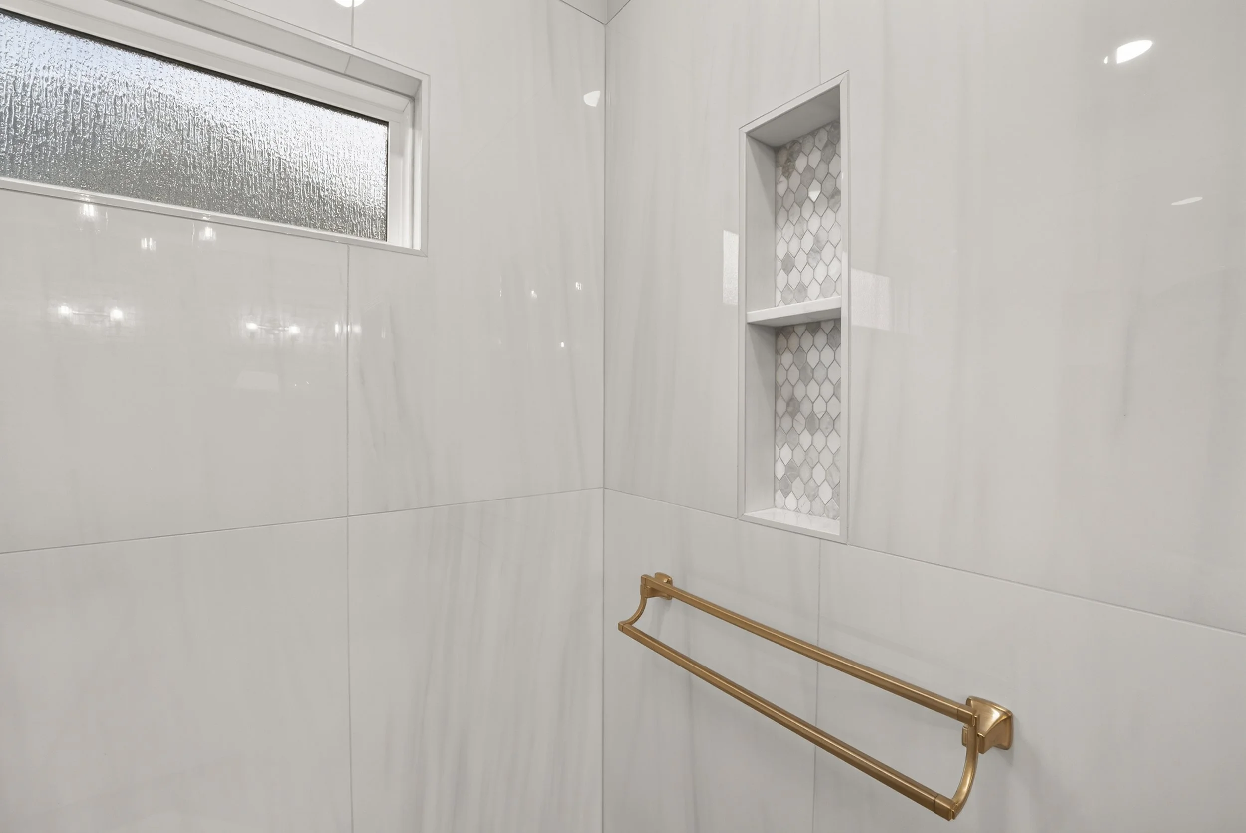 Gold towel bar in a curbless shower.