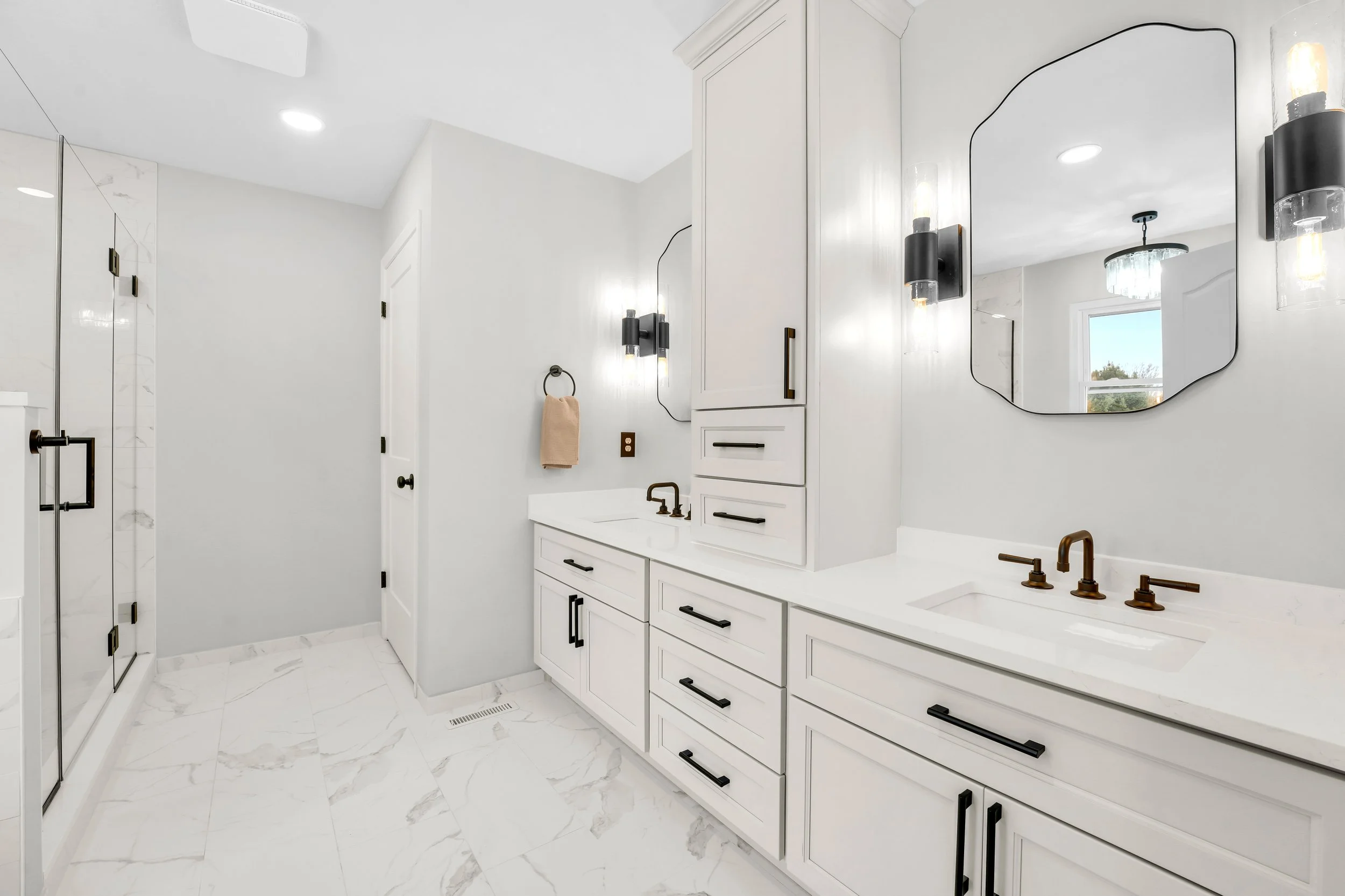 Gray double vanity with storage tower and a shower on opposite wall