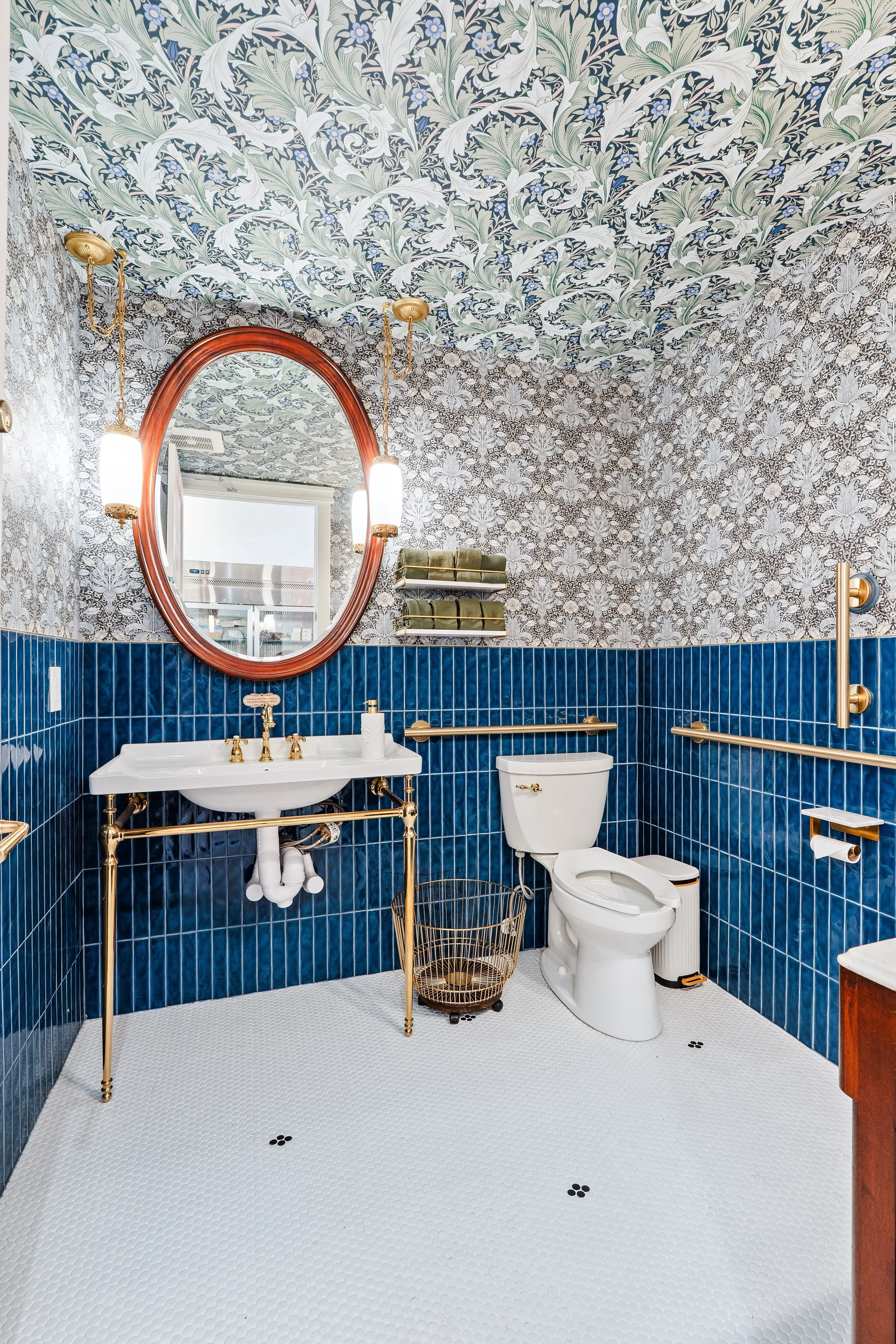 Dark blue bathroom wall tile with vintage inspired sink and gold plumbing fixtures.