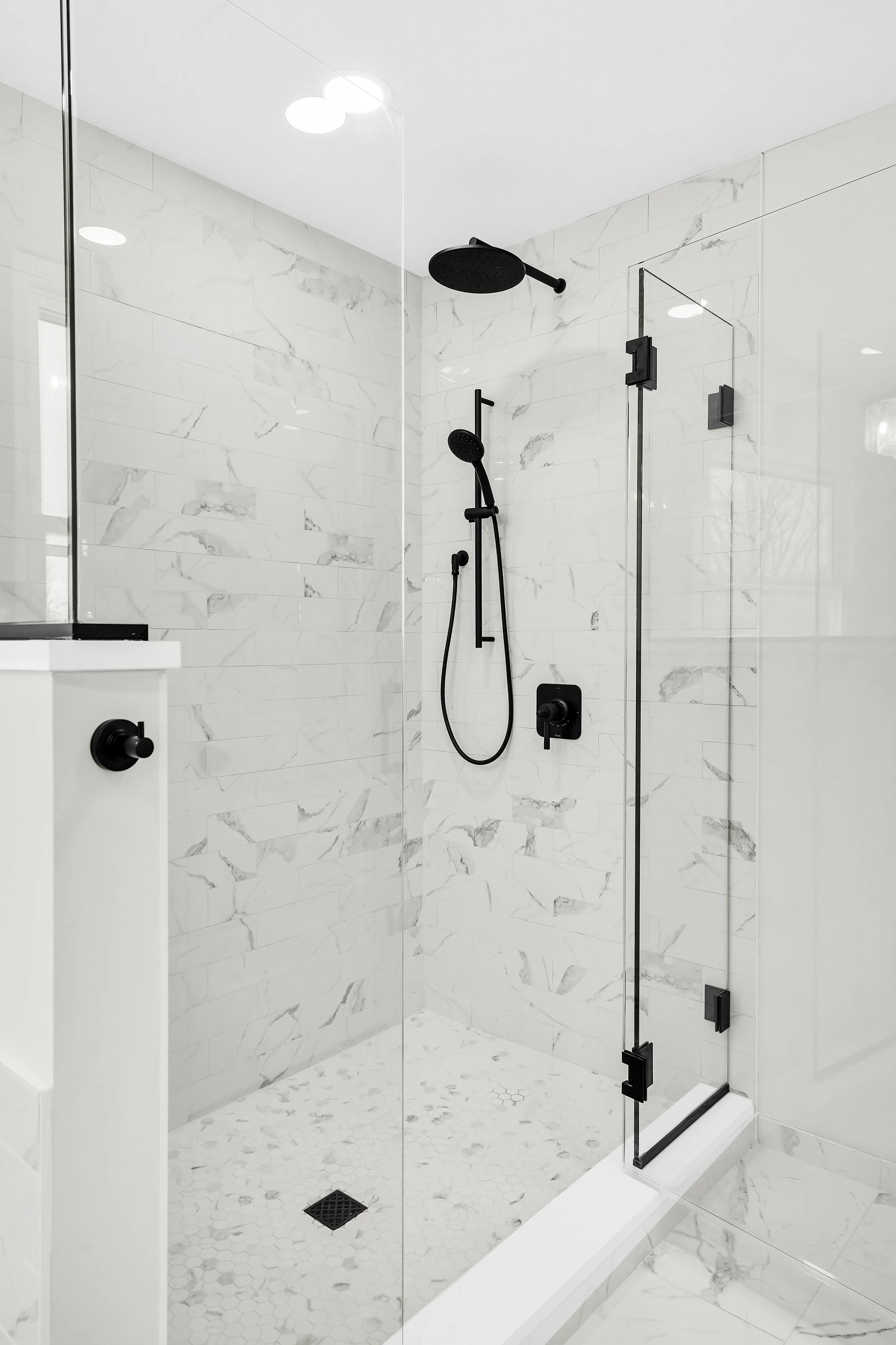 Marble shower with mosaic tile floor and black fixtures 