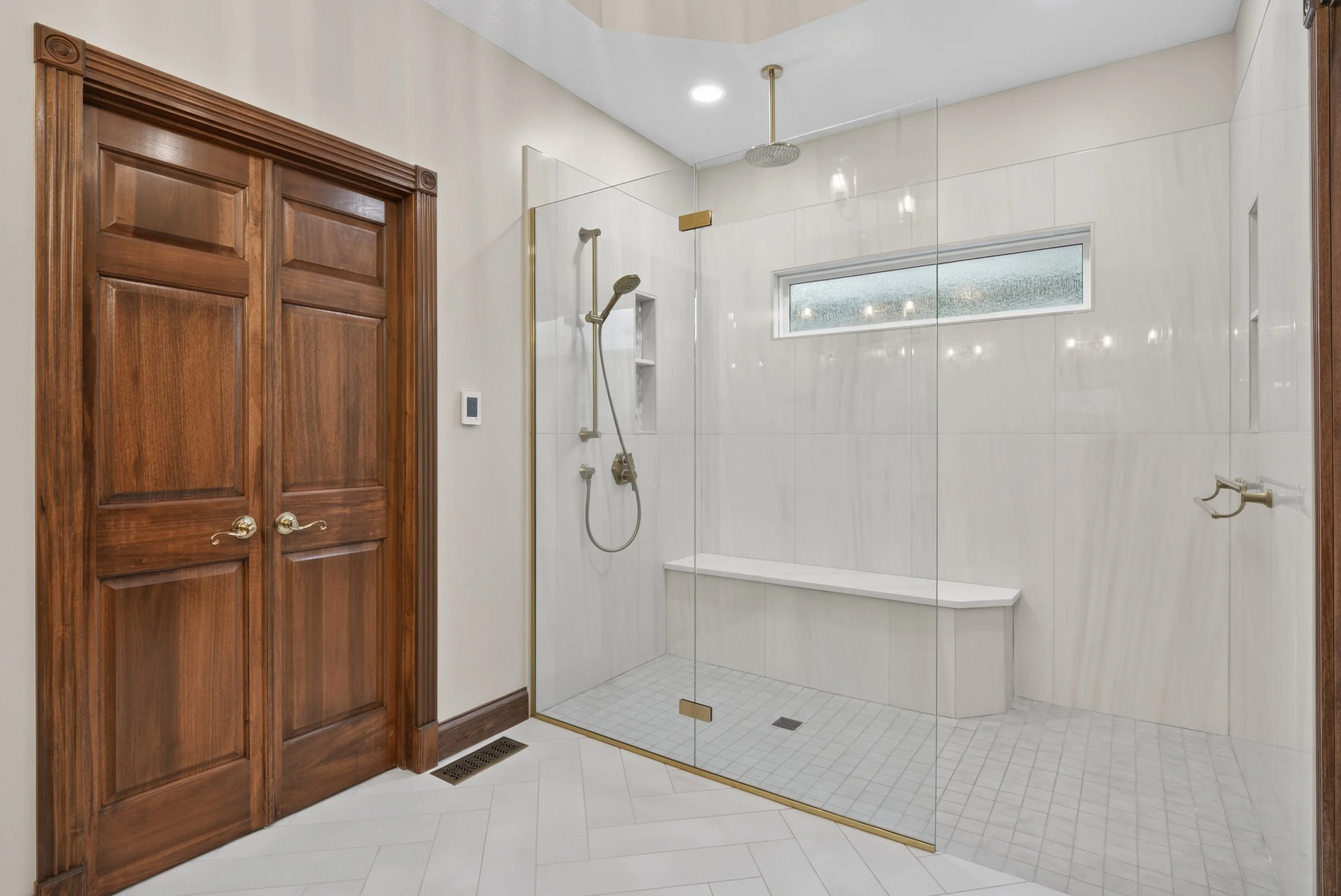Curbless shower with natural tiling and gold accents.