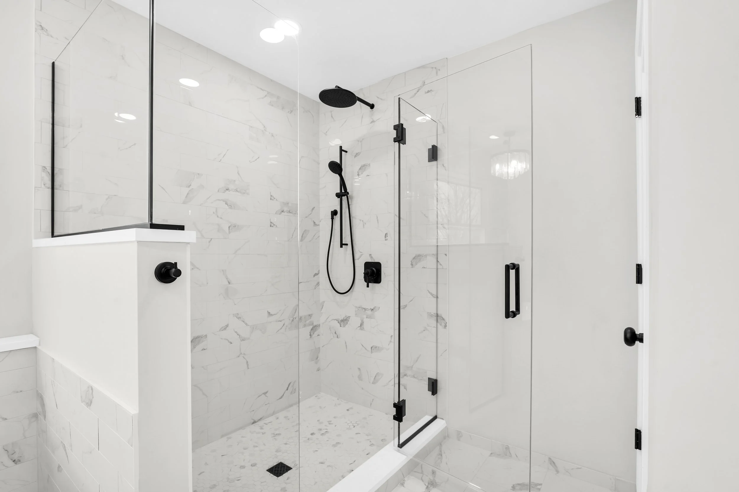 Marble shower with mosaic tile floor and black fixtures 