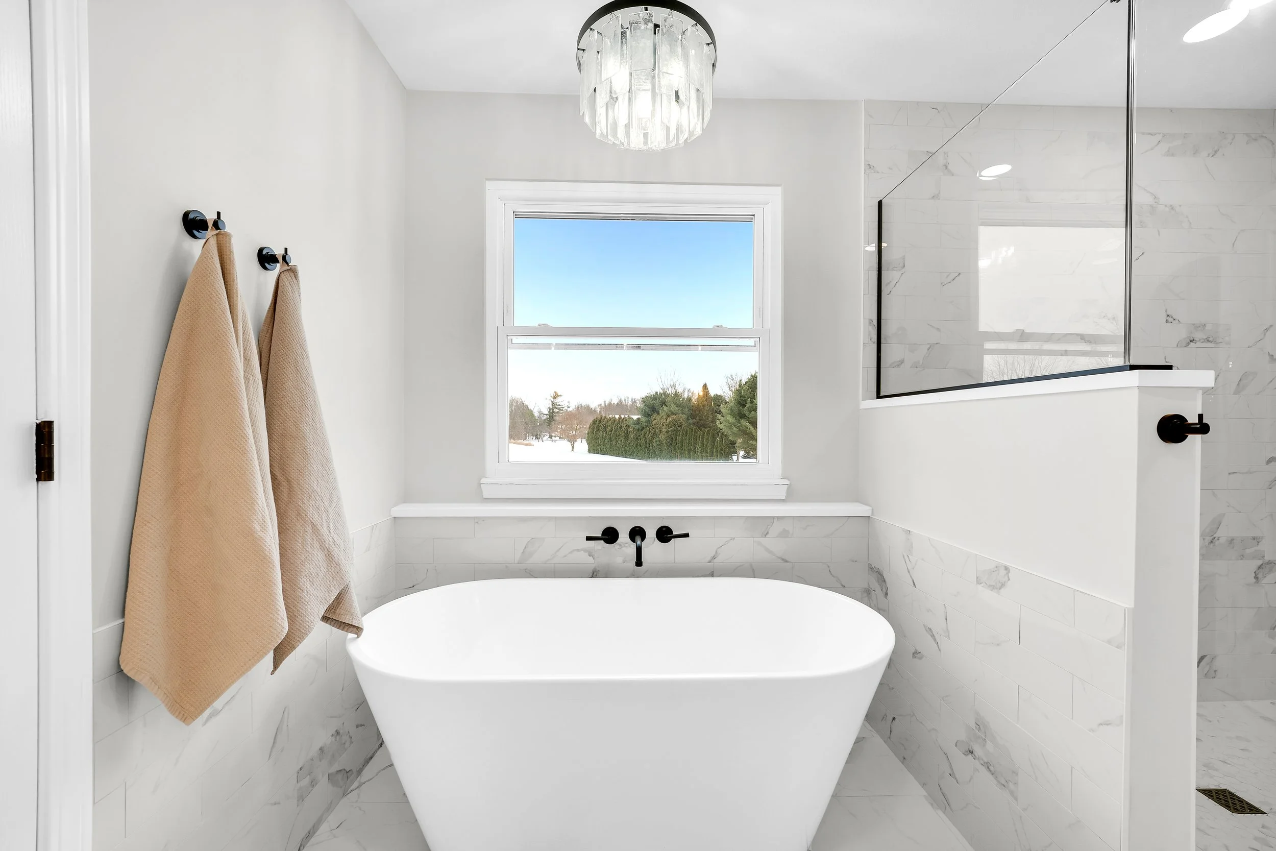 Freestanding modern tub next to built in tile shower