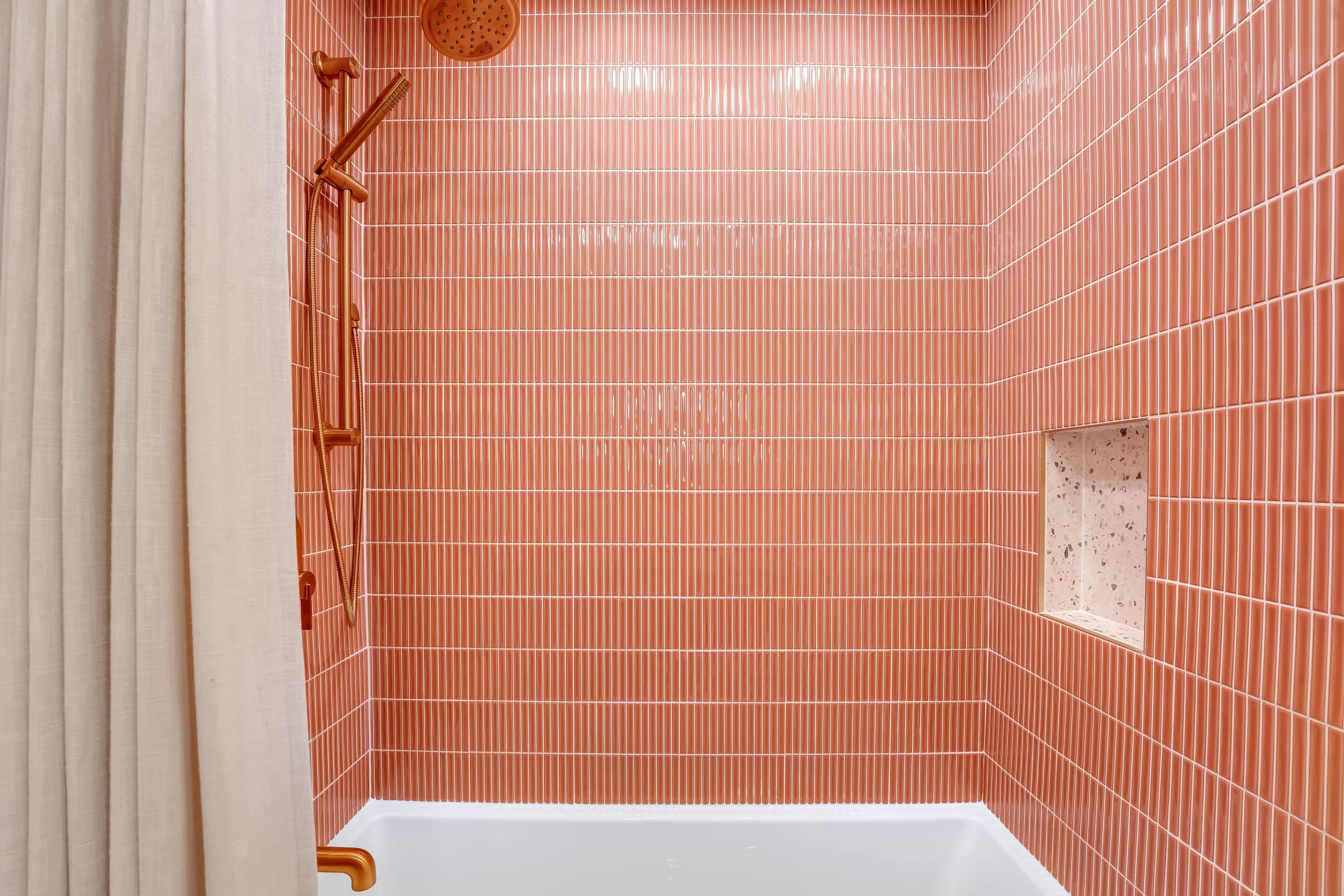 Coral colored tile tub surround with gold plumbing fixtures
