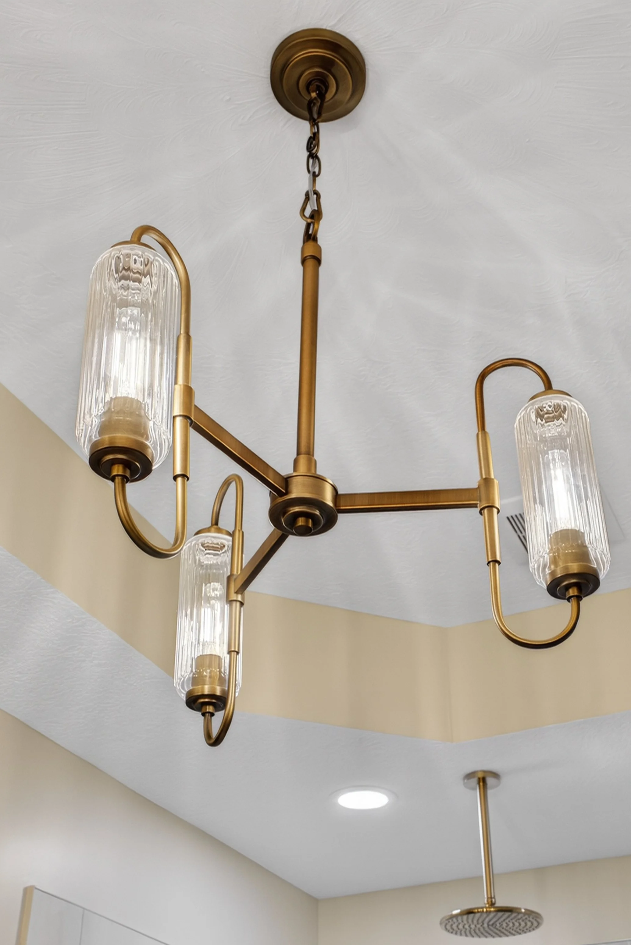 Three light gold chandelier in bathroom with fluted glass.