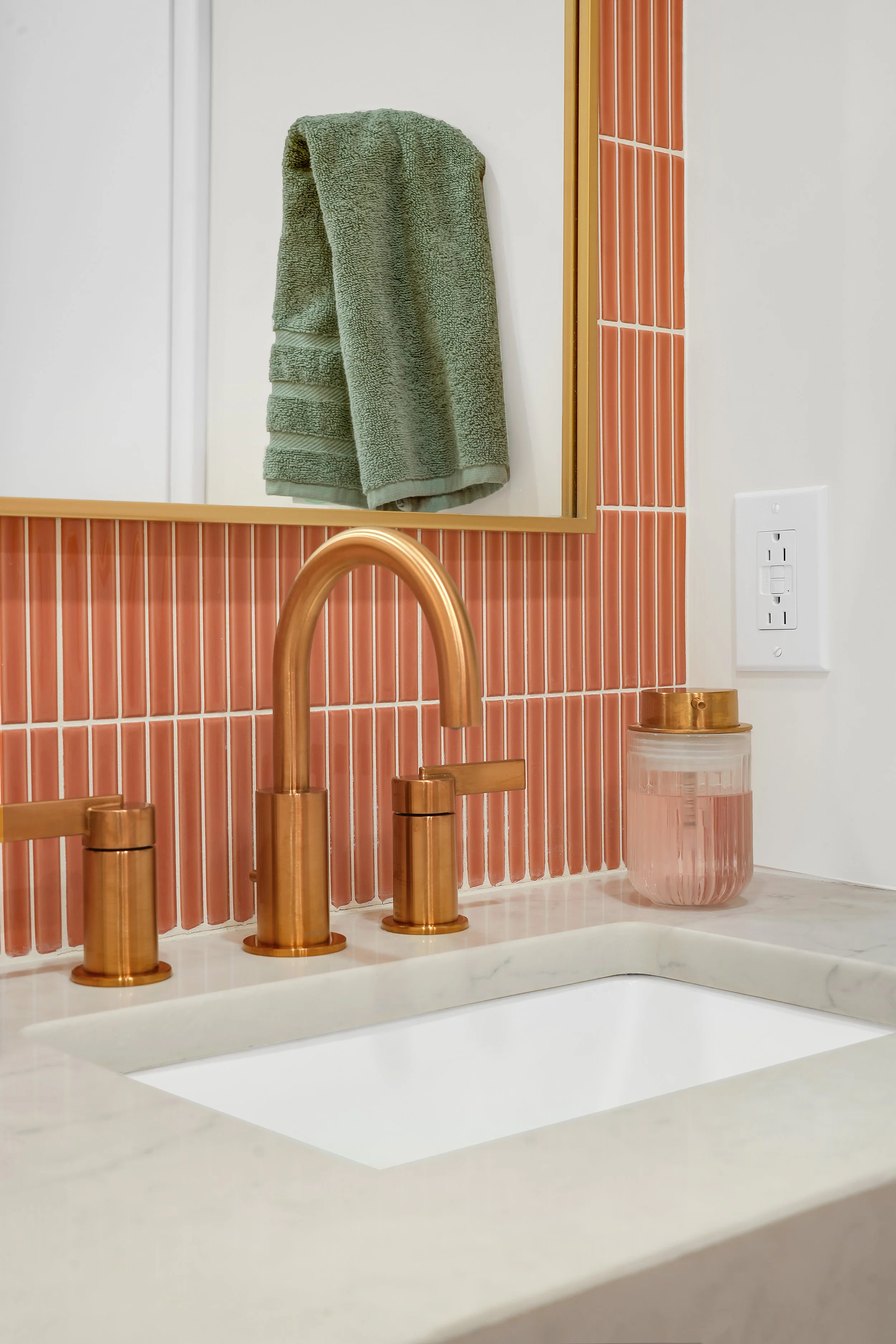 Coral tile backsplash with gold faucet