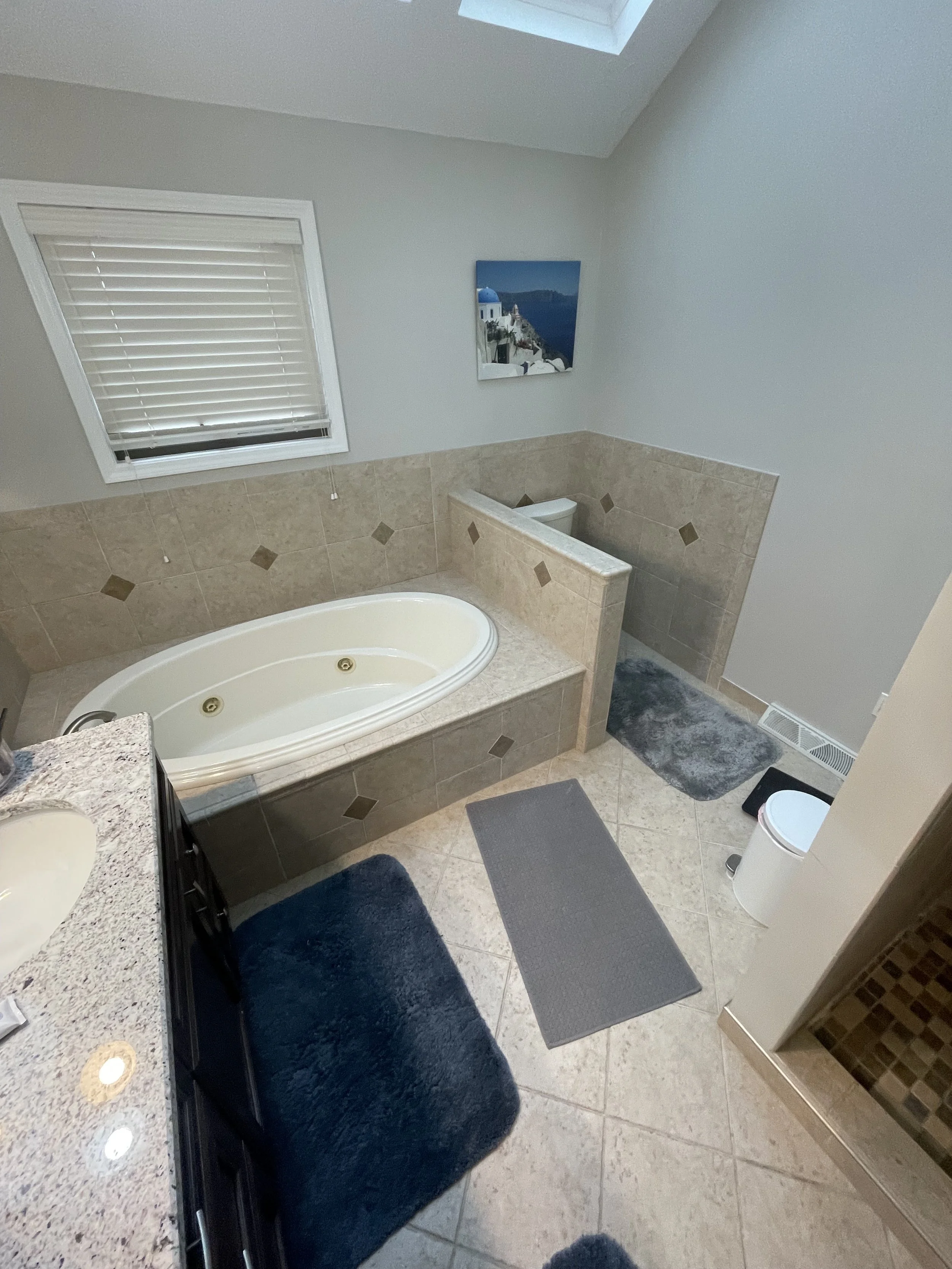 Built in jacuzzi tub with a toilet behind a half wall