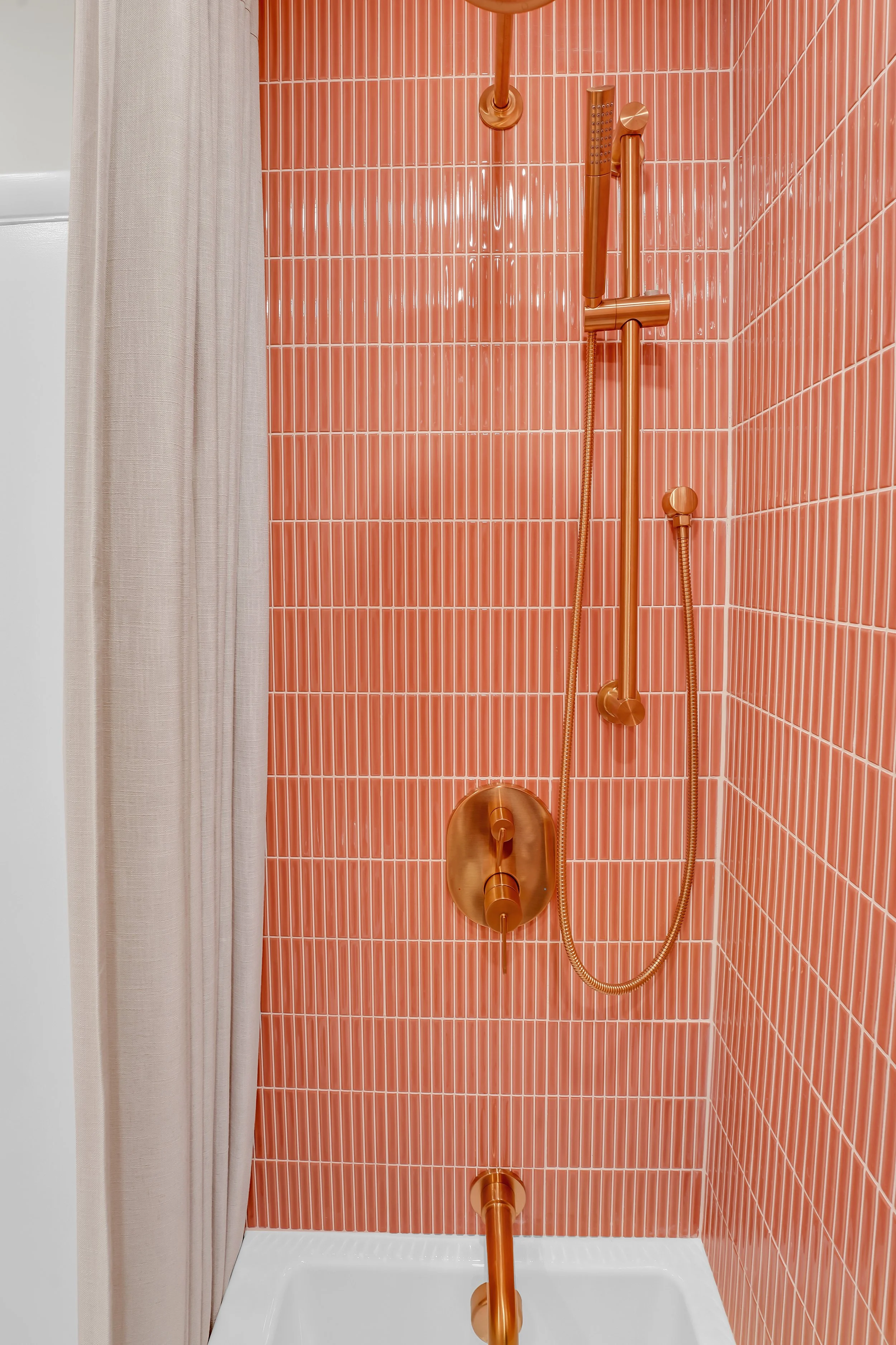 Coral colored tile tub surround with gold plumbing fixtures