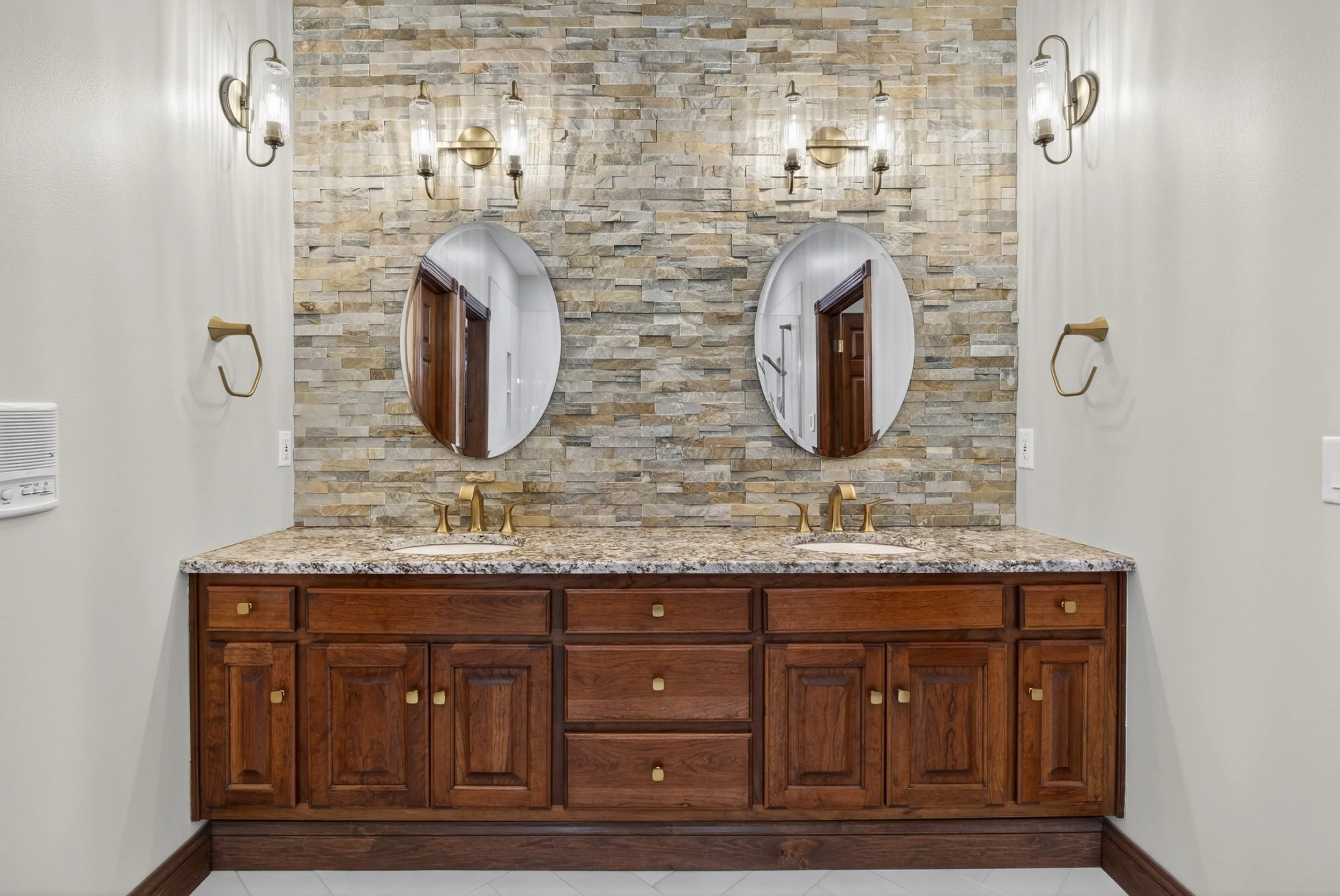 Double vanity with stacked stone wall backsplash to ceiling.