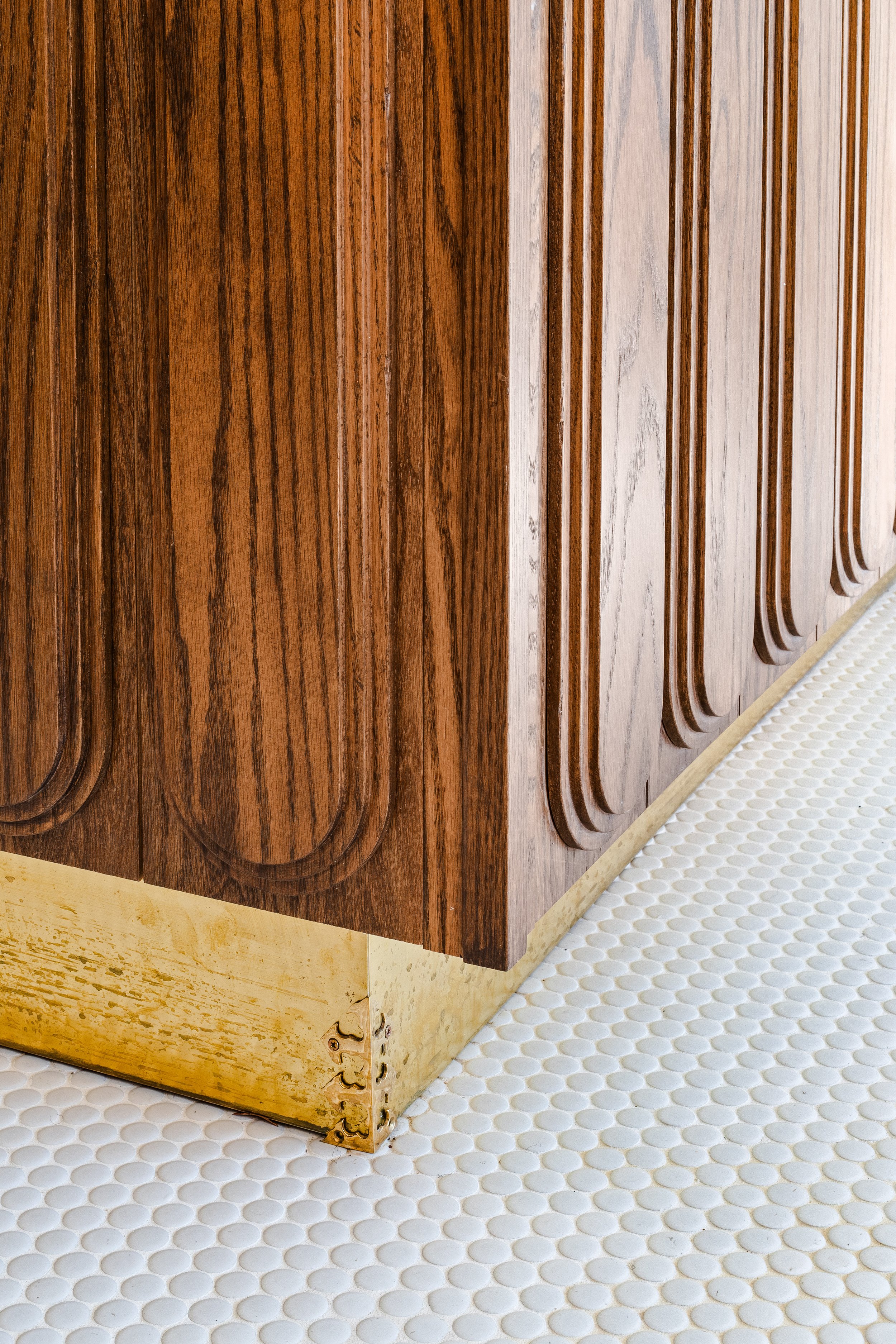Close up of brass toe kicks under the wooden custom cabinetry.