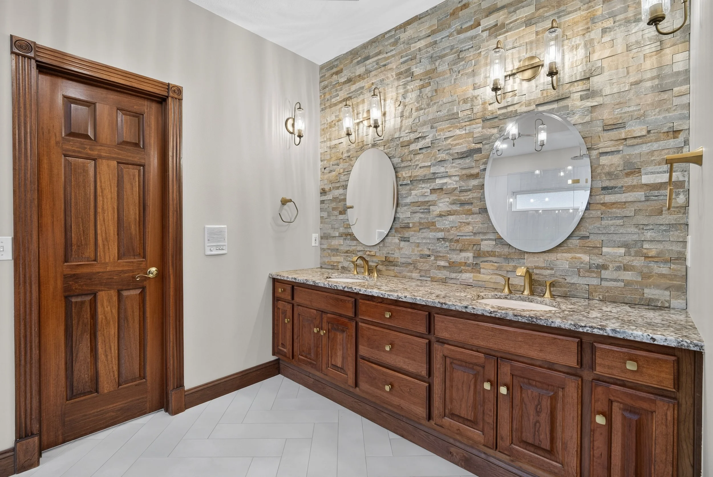 Double vanity with stacked stone wall backsplash to ceiling.
