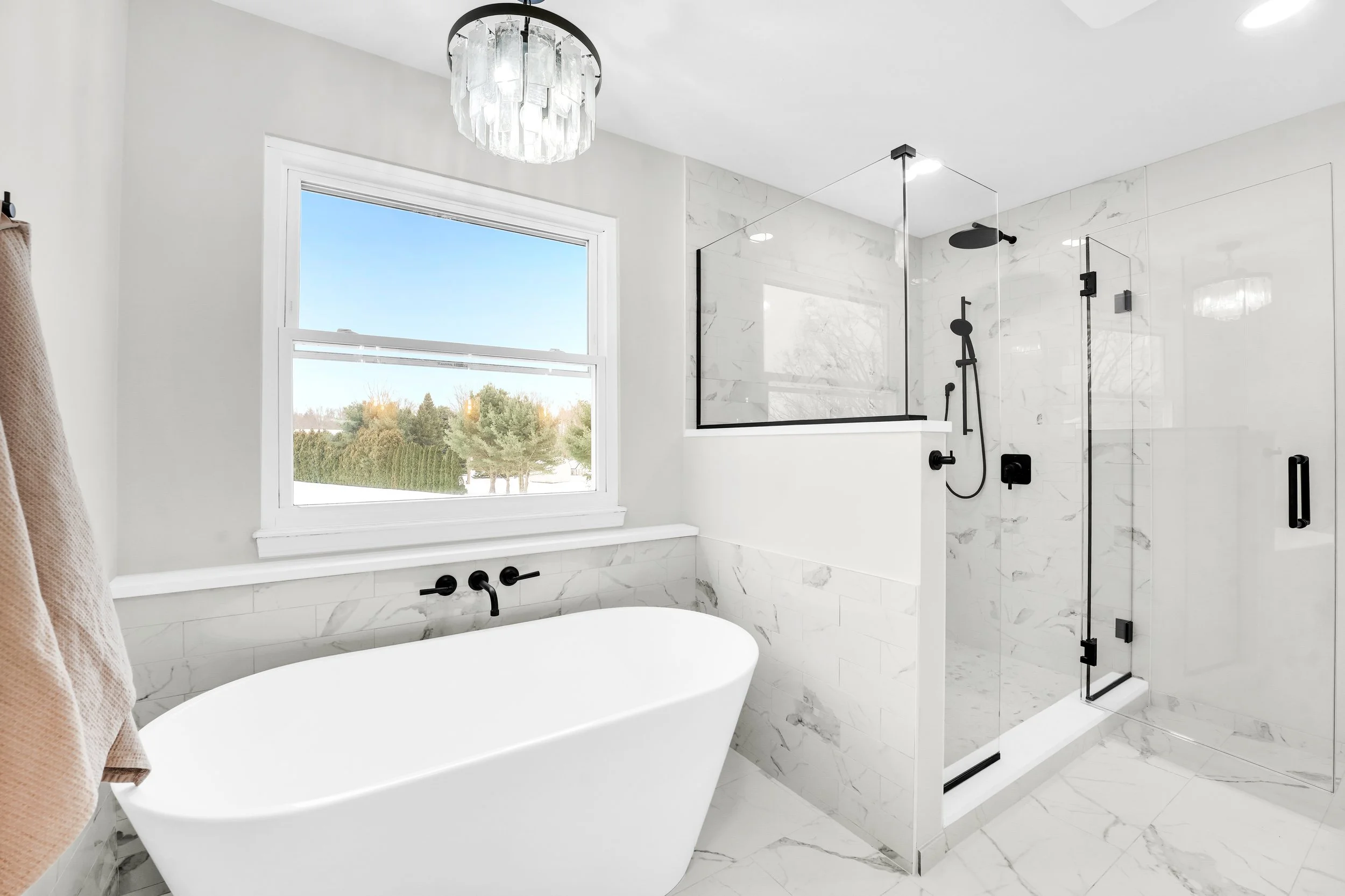 Shower and freestanding tub along the wall of a master suite
