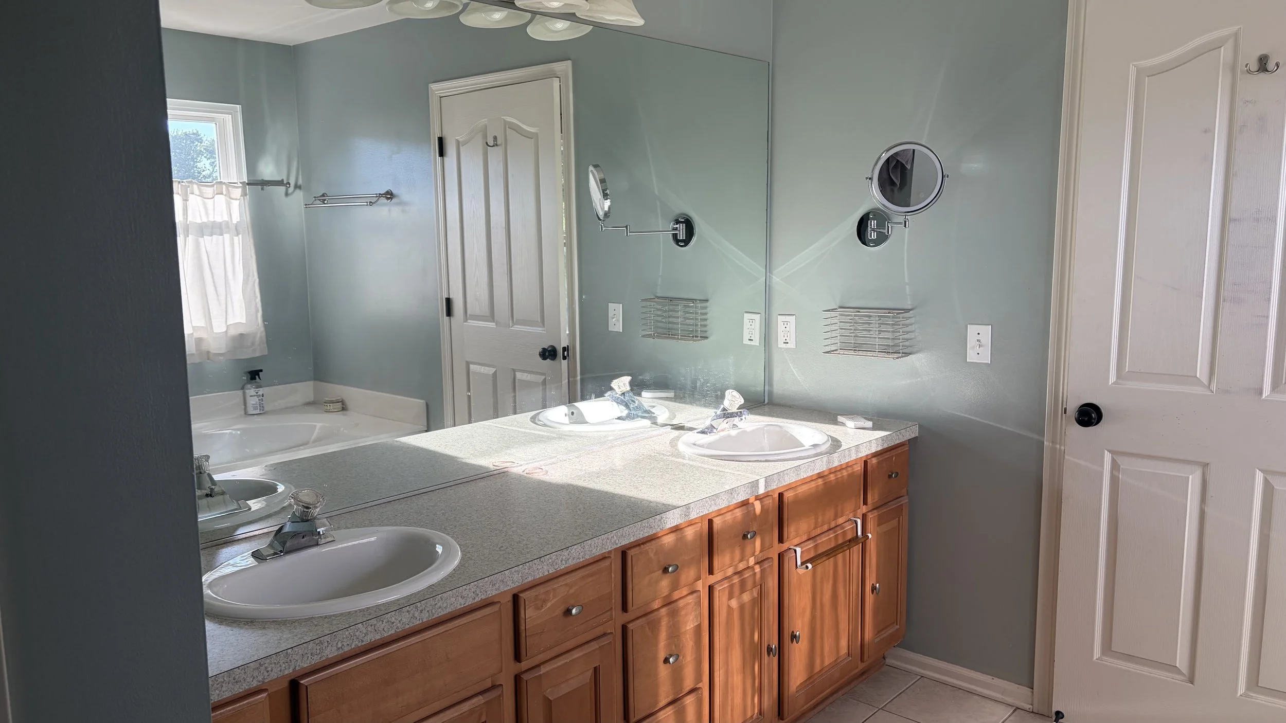 Pre-renovation photo of builder grade cabinets with laminate countertops in a master bathroom