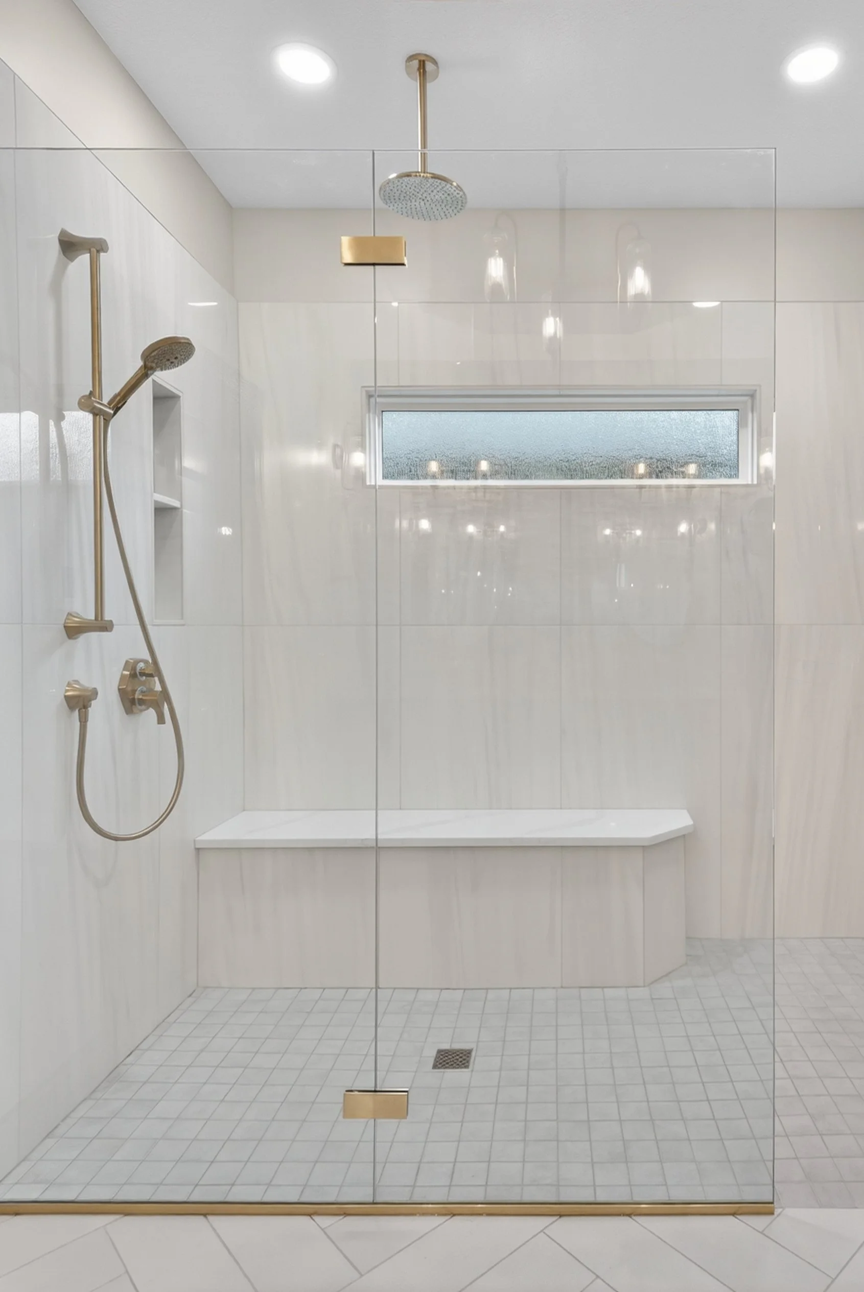 Curbless shower with glass door and a bench in the shower.