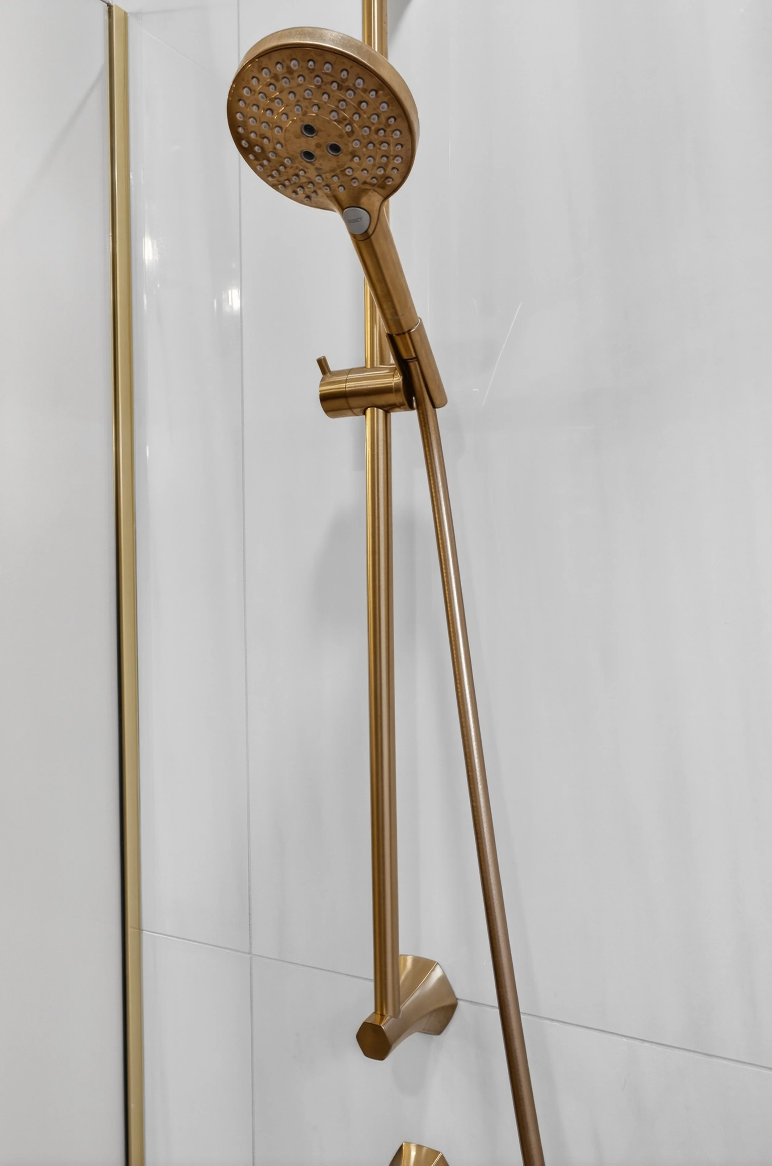 Handheld gold shower head on adjustment bar.