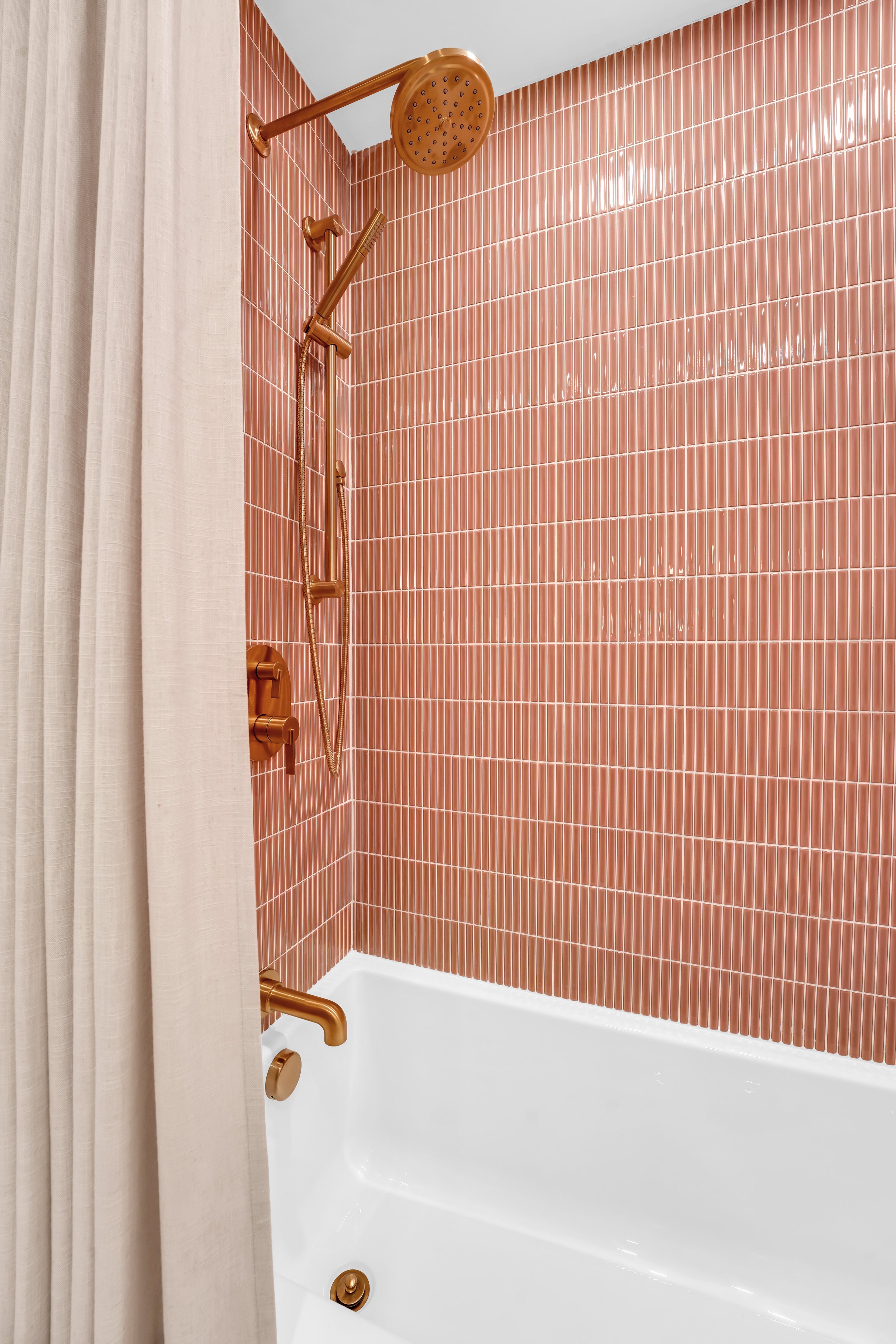 Coral colored tile tub surround with gold plumbing fixtures