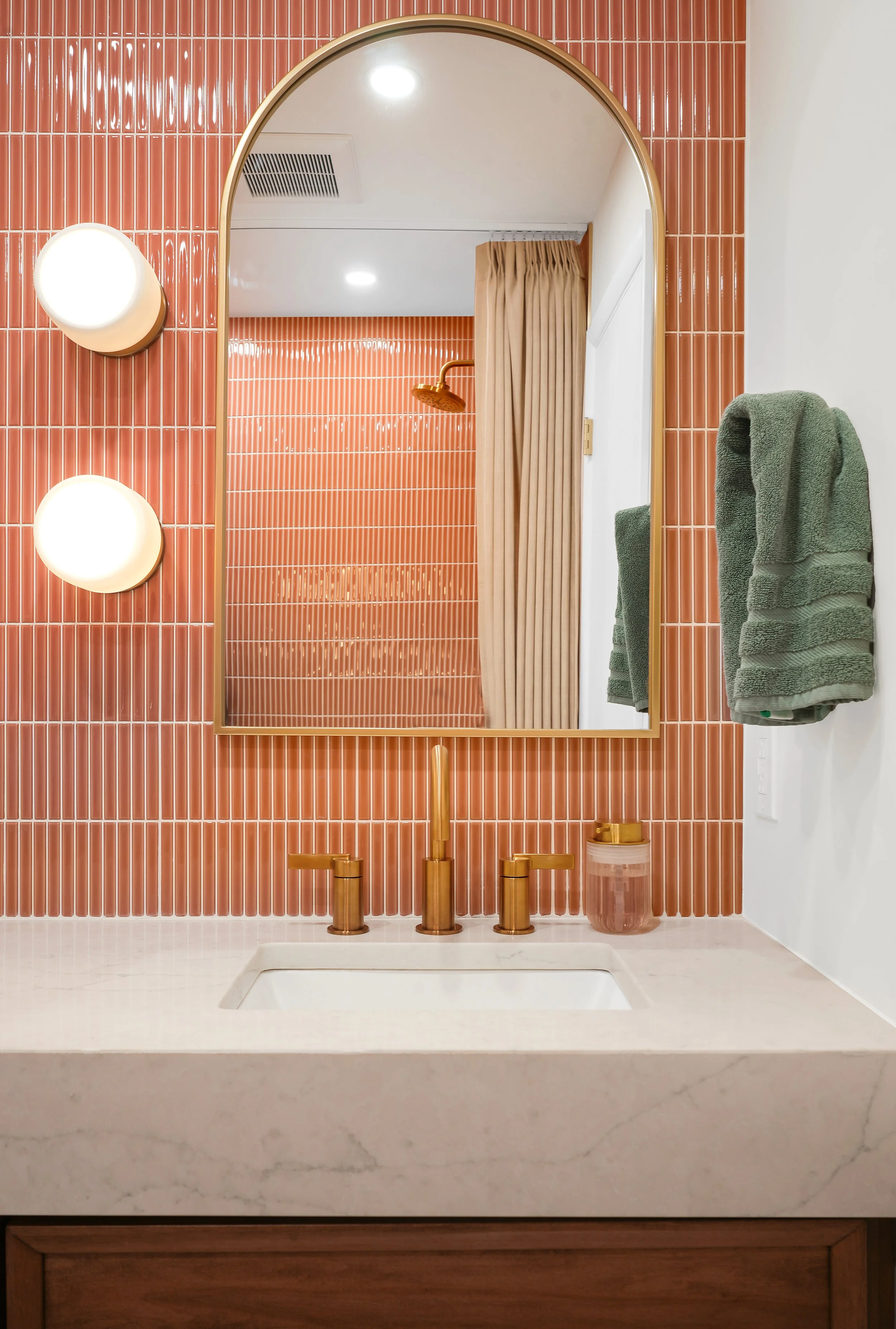 Wall to wall vanity with coral colored backsplash designed by Sebastian Reymers and Heimat Design and Renovation