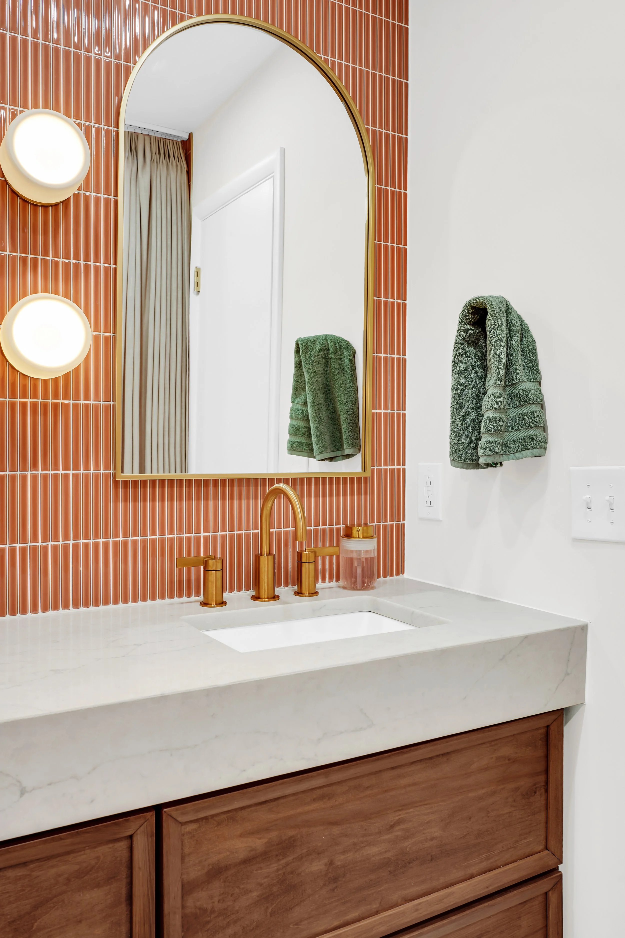 Coral tile backsplash with gold faucet and vanity mirror