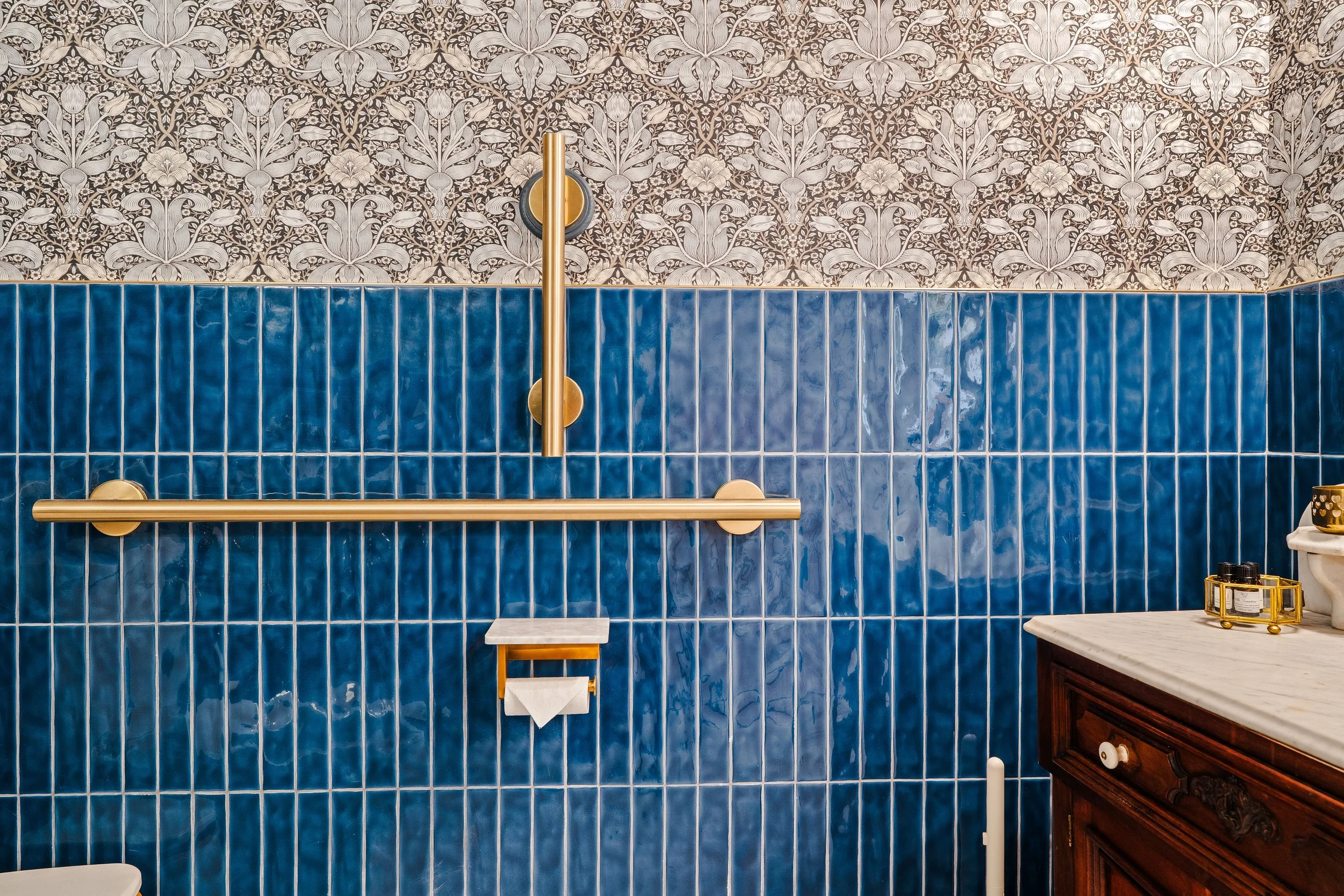 Dark blue bathroom wall tile with gold fixtures.