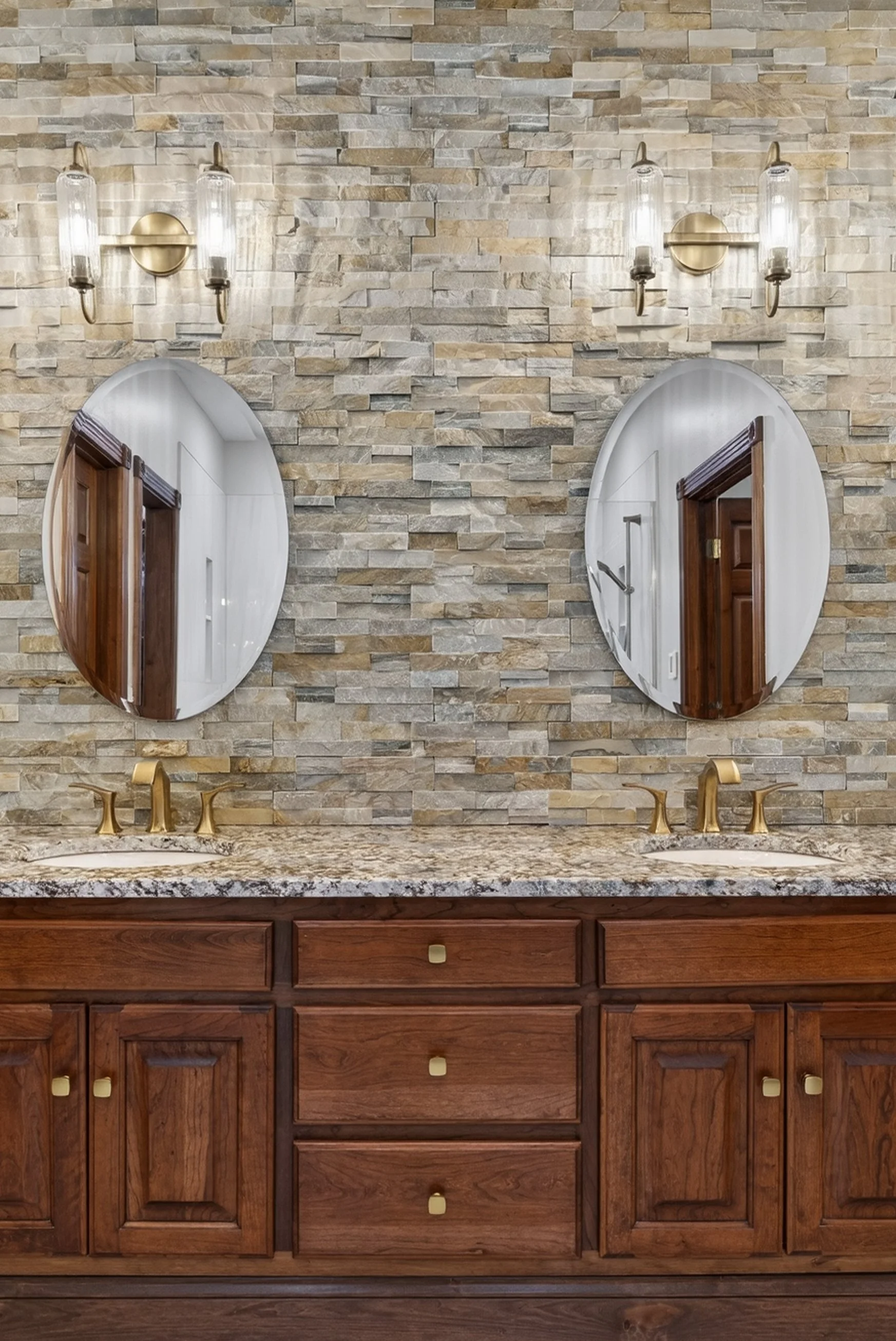 Double vanity with stacked stone wall backsplash to ceiling.
