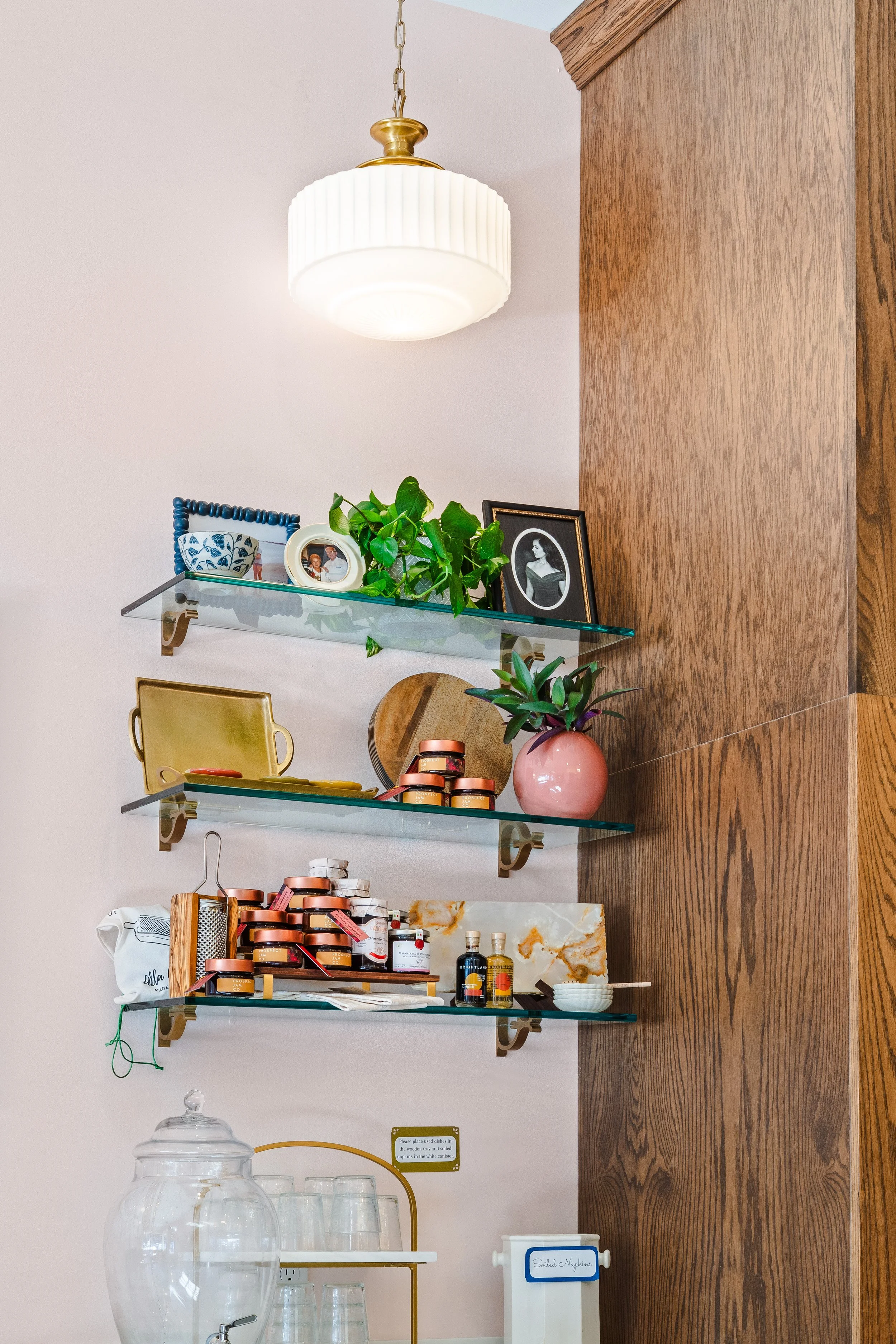 Open glass shelving along the wall over built in cabinetry.