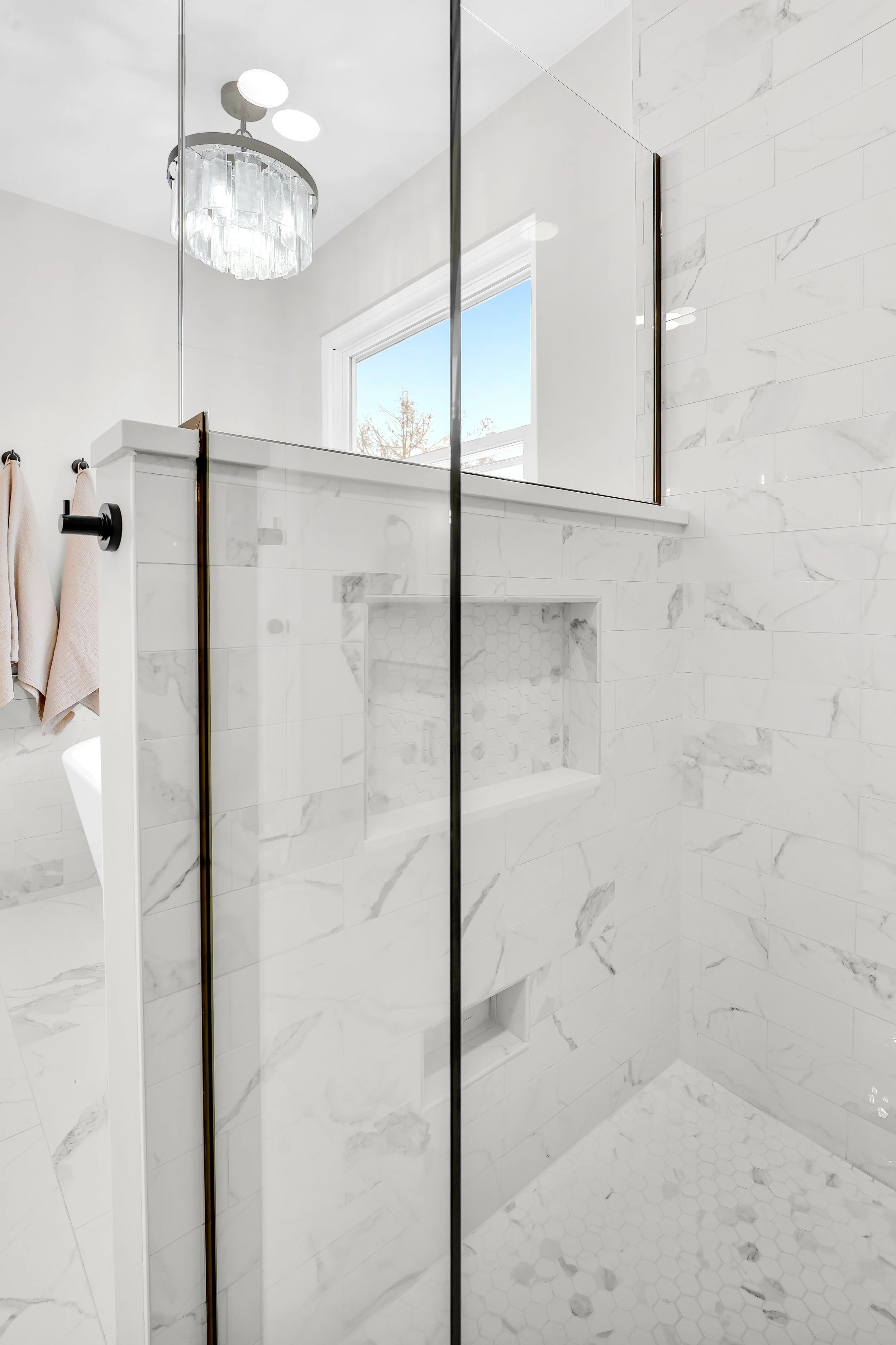 Hidden shower niche along a half wall in the shower and a foot niche for shaving