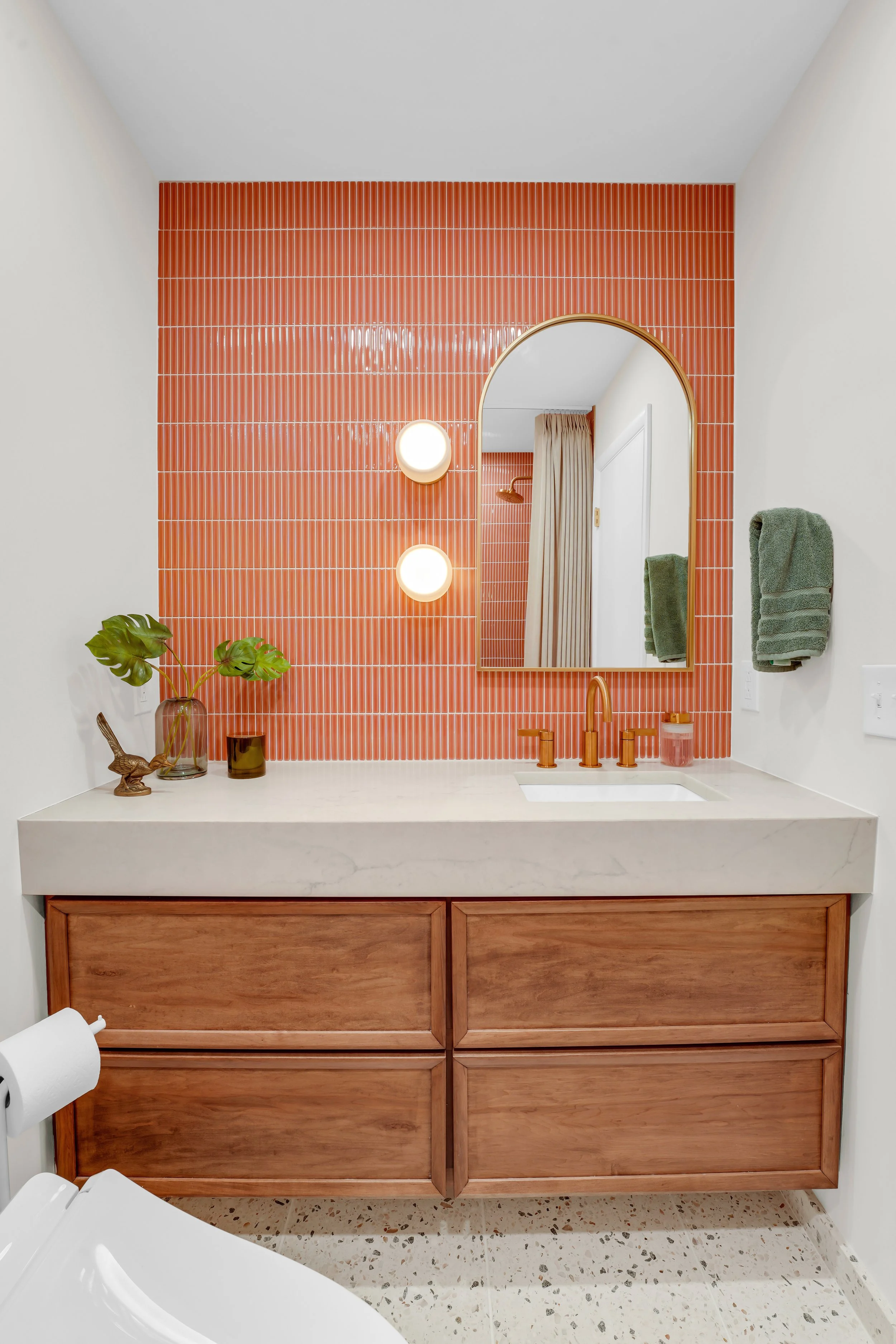Wall to wall vanity with coral colored backsplash designed by Sebastian Reymers and Heimat Design and Renovation