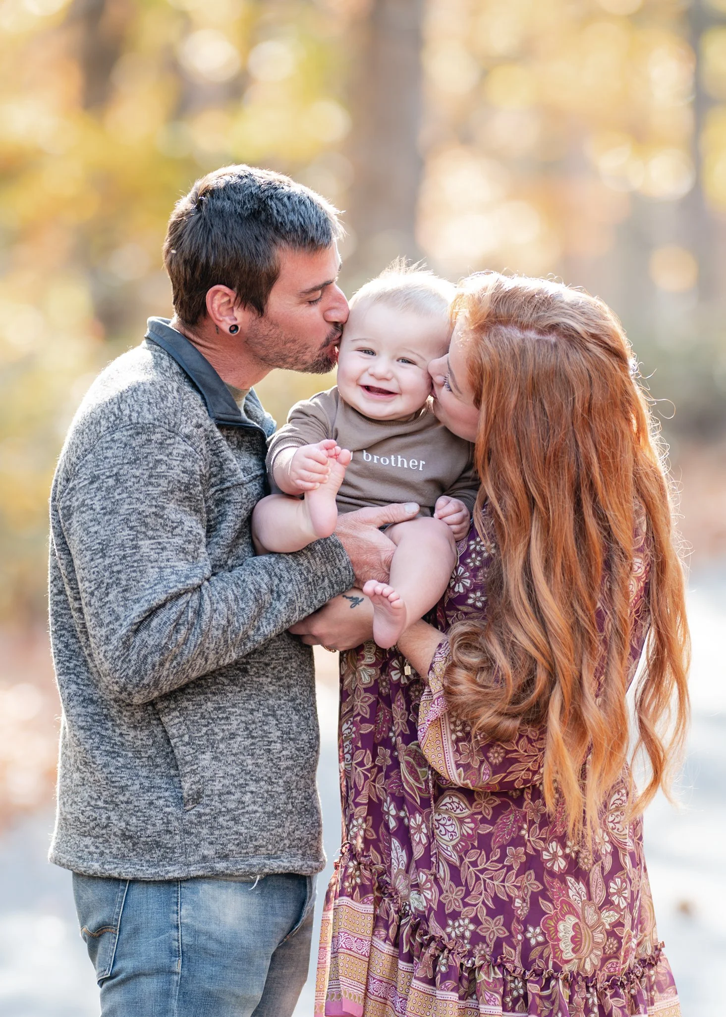 Parents kissing their smiling baby outdoors