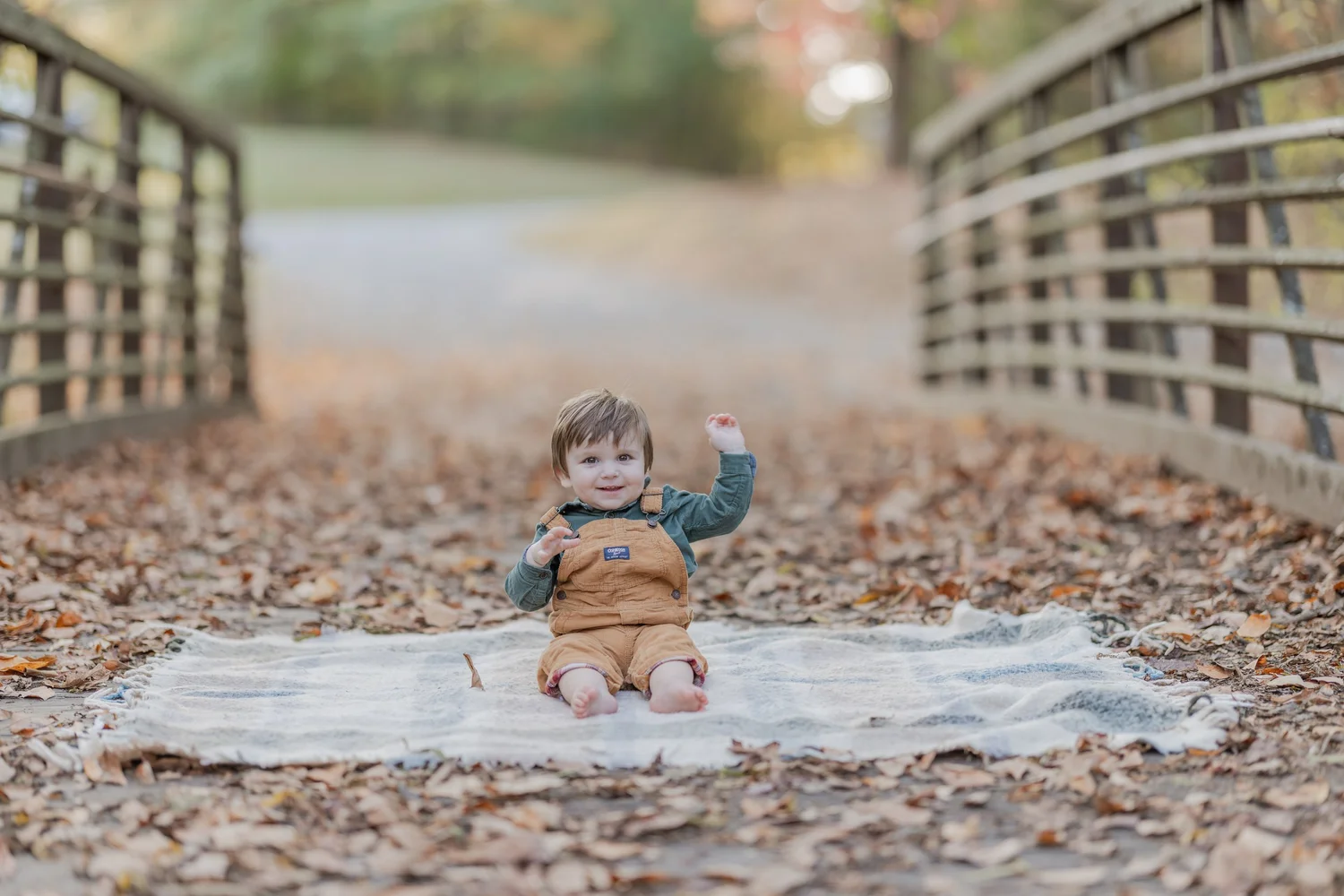 Child seated on a blanket along a wooded path