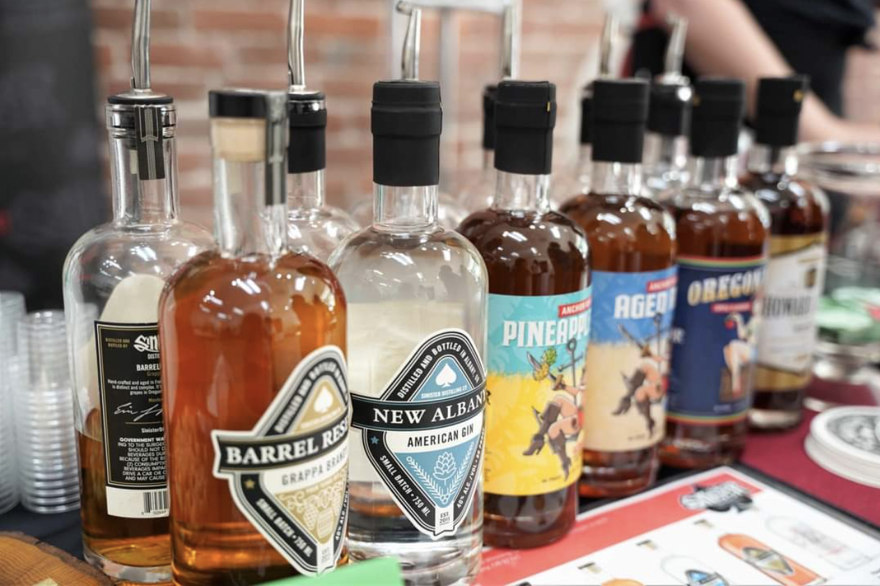 A row of bottles from Sinister Distilling at an outdoor market.