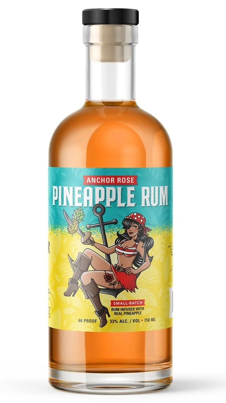 A bottle of Anchor Rose Pineapple Rum with a colorful label featuring a vintage pin-up style woman in a red and white striped bikini top, red skirt, and boots, sitting next to an anchor and holding a pineapple. The label states it is small-batch rum infused with real pineapple, 66 proof, 33% alcohol, 750 ml.