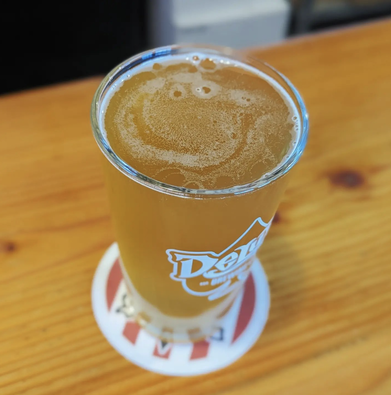 A glass of Deluxe beer on a wooden table.