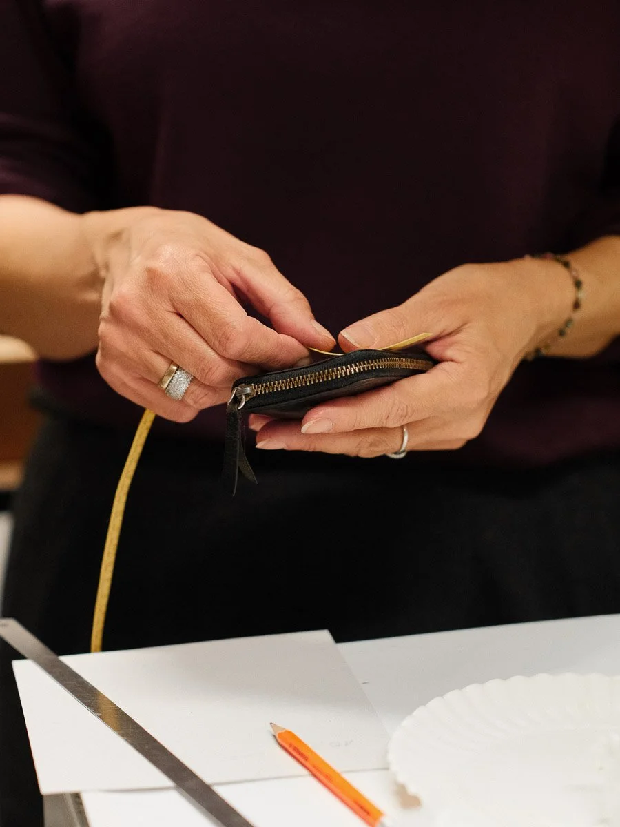 Hands measuring a leather wallet.