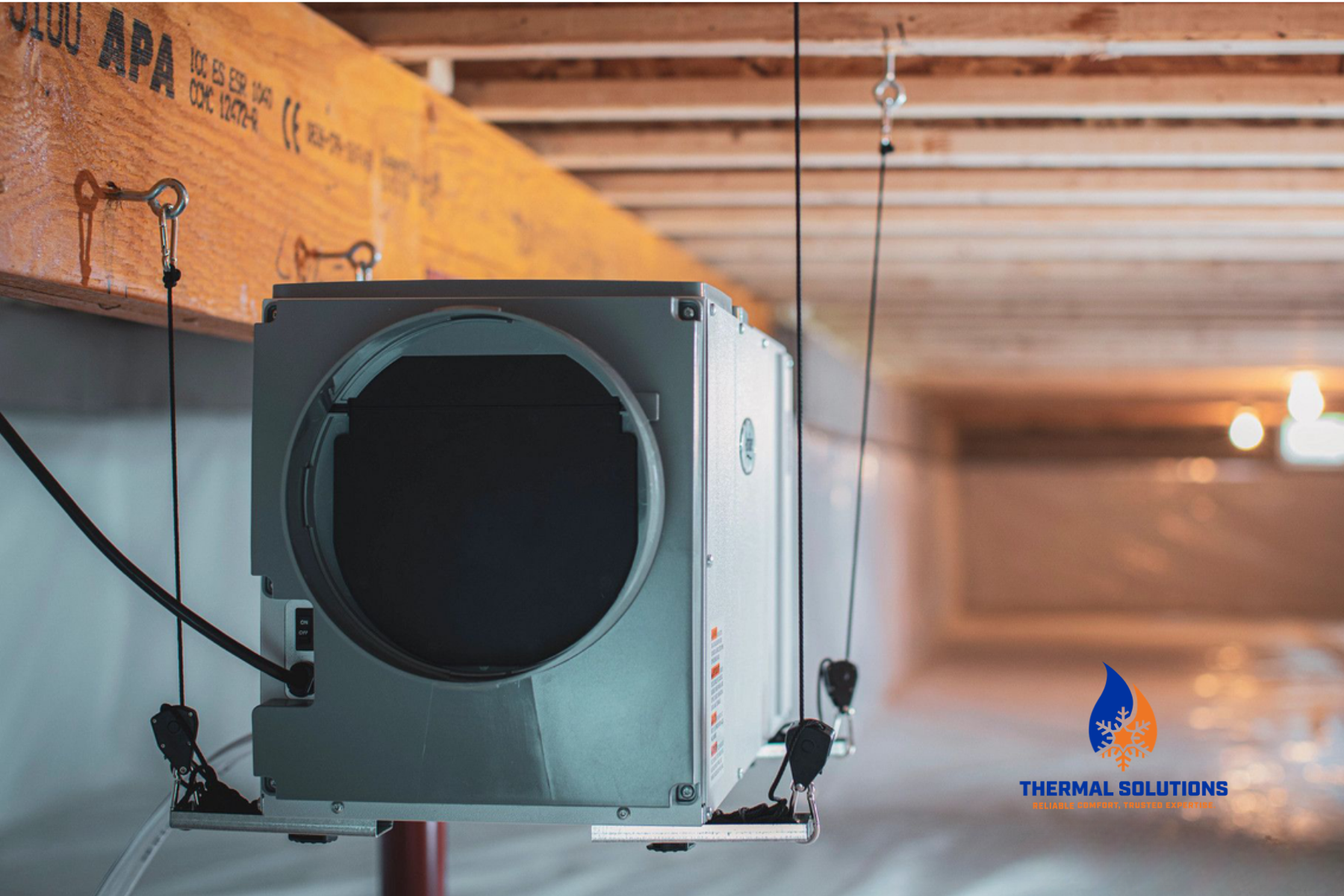 An dehumidifier installed on a suspended platform in a  crawl space. The machine is part of a reliable heating system, indicated by the 'Thermal Solutions' logo at the bottom right corner.