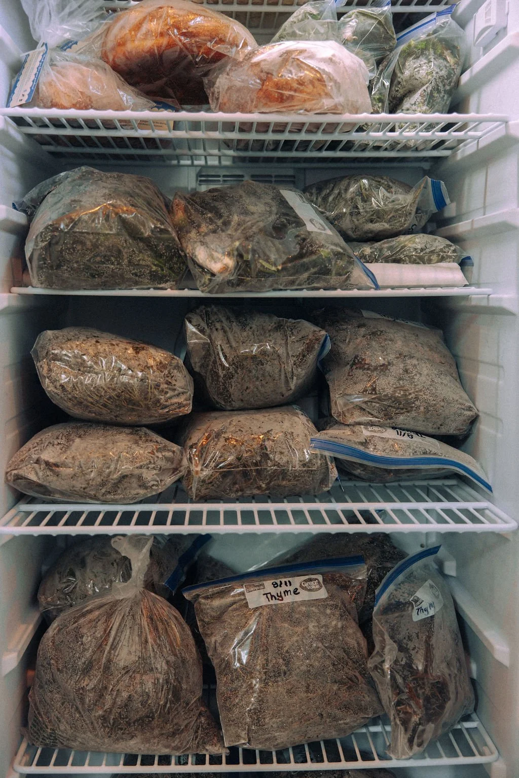 Multiple plastic bags filled with dried herbs stored in a refrigerator.
