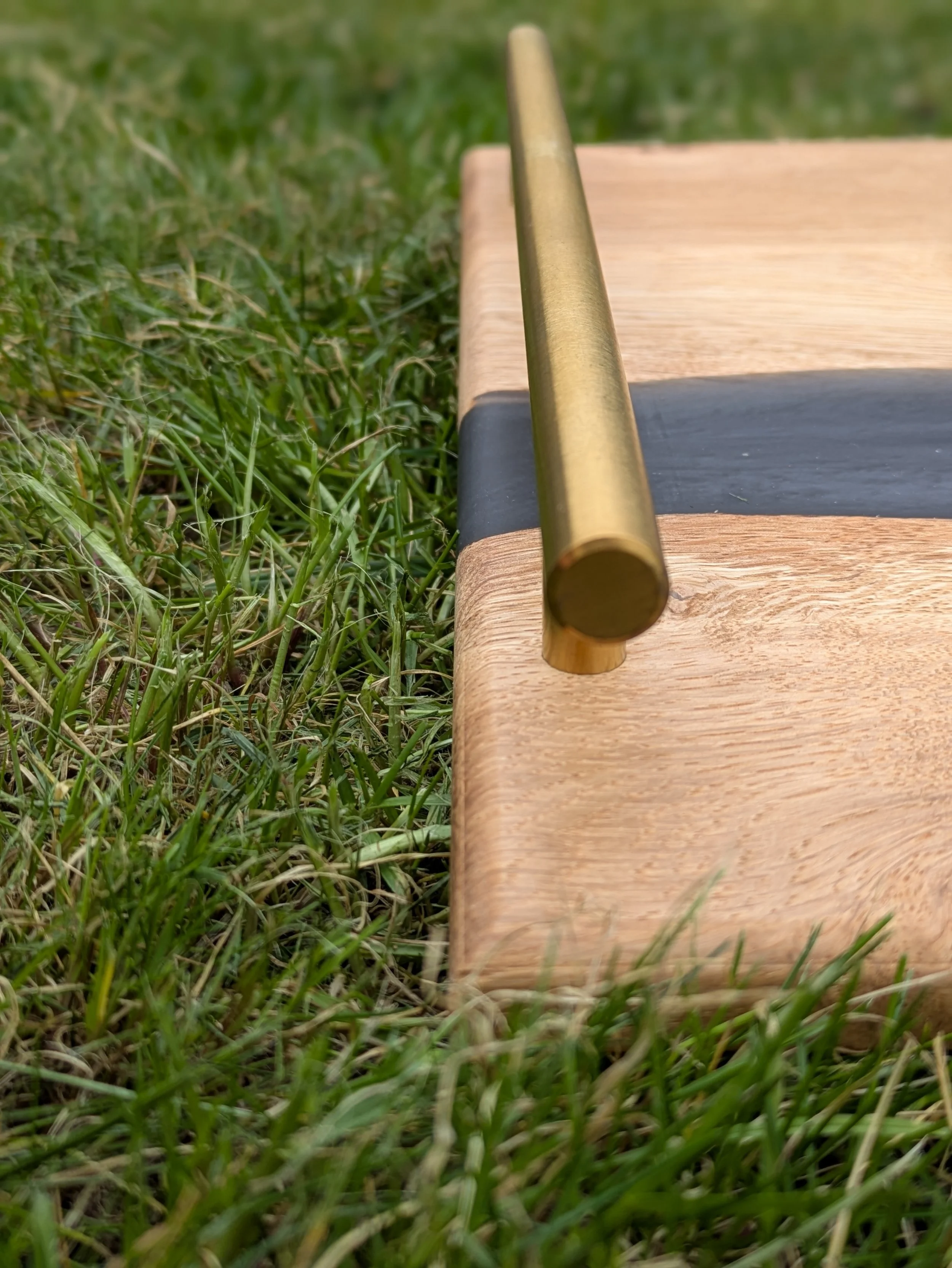 Close-up of a brass pole on a wooden board, with grass surrounding it.