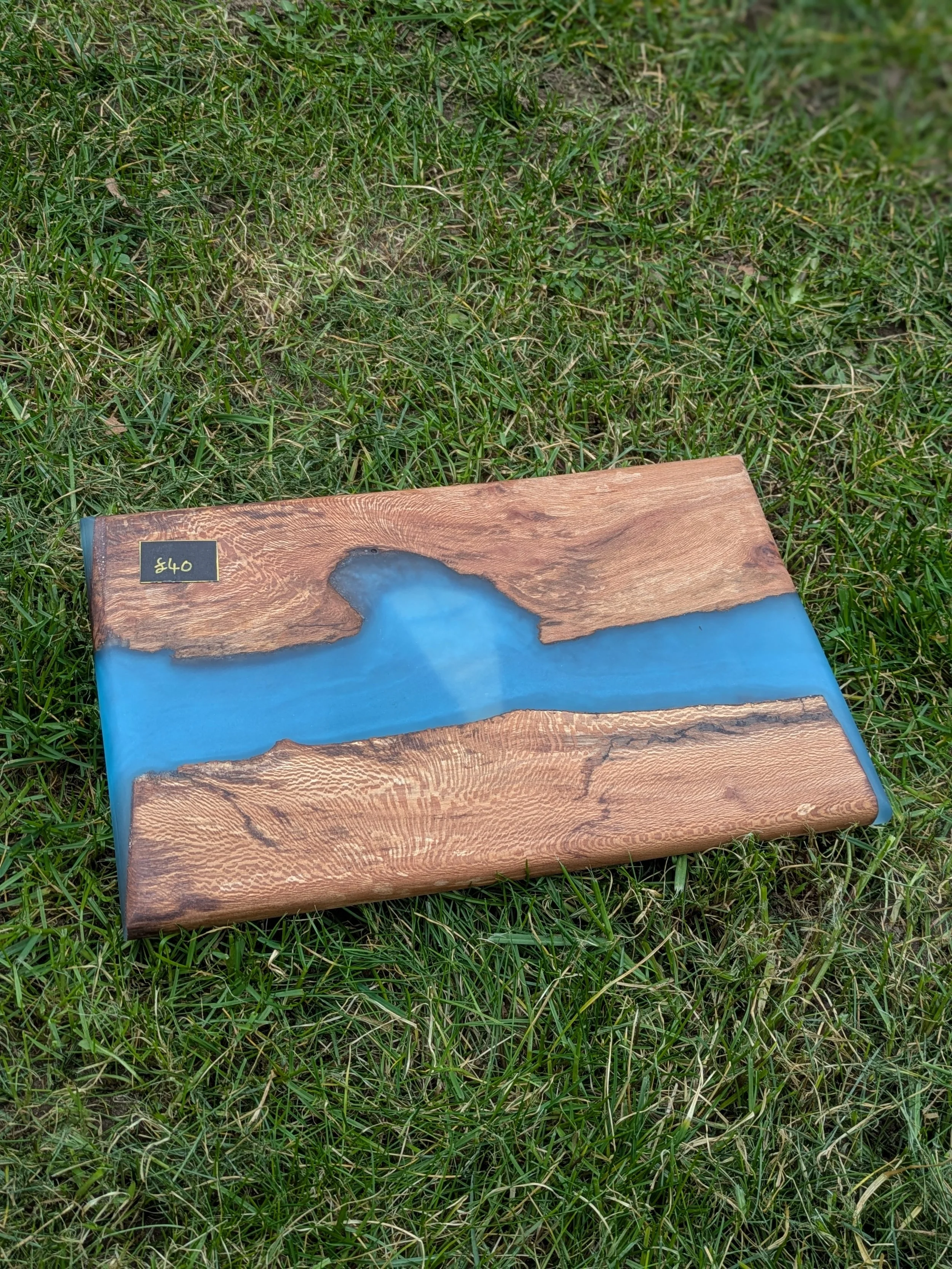 Close-up of a wooden table with a small black price tag showing $40 on a grassy outdoor surface.