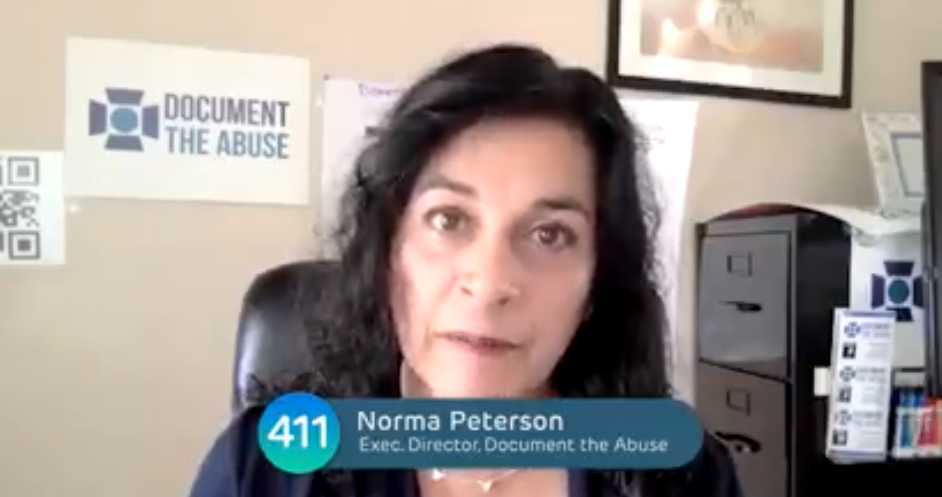 Norma Peterson, Executive Director of Document the Abuse, speaking in an office with a sign that reads "DOCUMENT THE ABUSE" on the wall behind her.