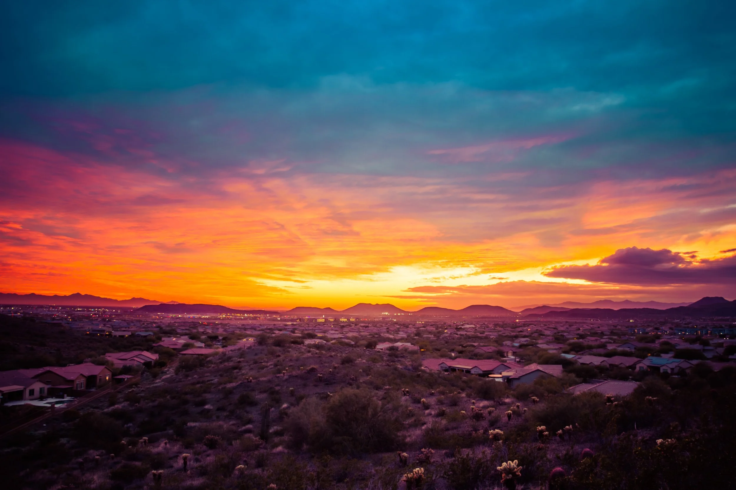 Vibrant Arizona desert sunset over suburban rooftops with glowing orange and purple sky, example of a high-selling stock landscape photo capturing dramatic evening light.